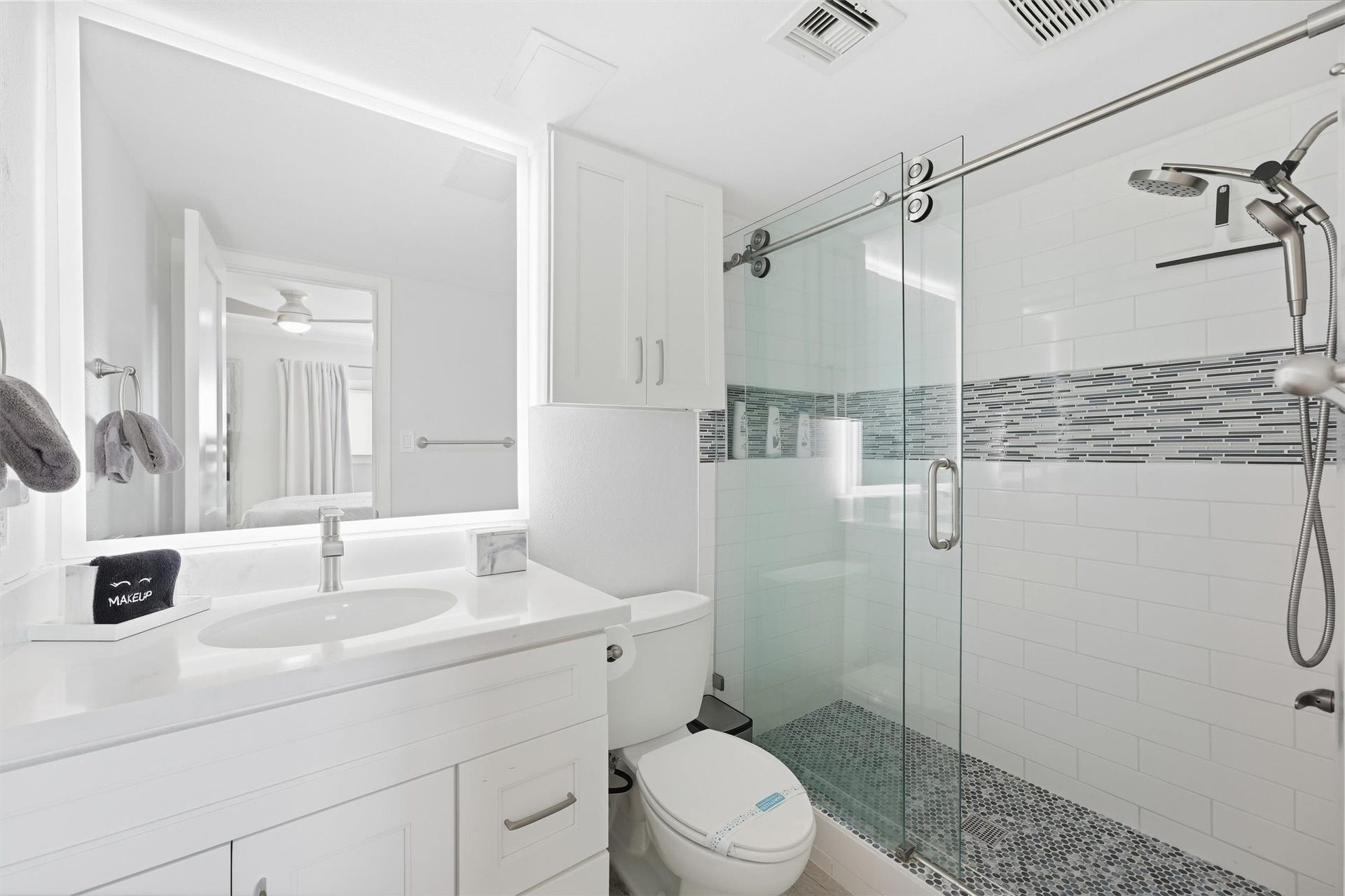 7310 Seawall Boulevard, #1105, Galveston, TX 77551 Bright and modern bathroom featuring a sleek glass-enclosed shower with stylish tile accents, a large mirrored vanity, and ample storage.
