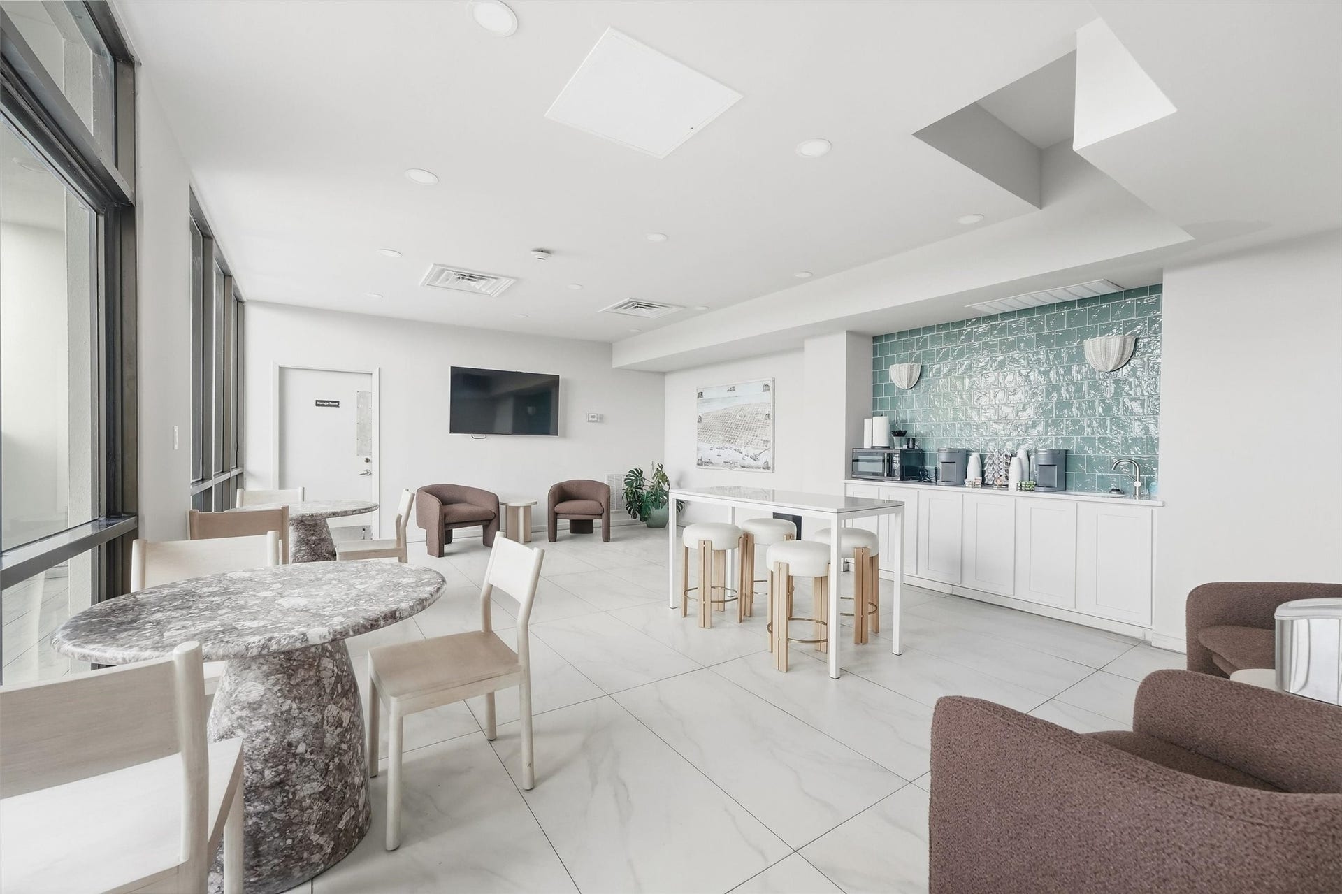 7310 Seawall Boulevard, #1105, Galveston, TX 77551 Bright and modern communal space featuring sleek tile floors, a cozy seating area, and a stylish kitchenette with a turquoise backsplash, perfect for socializing or enjoying a coffee.
