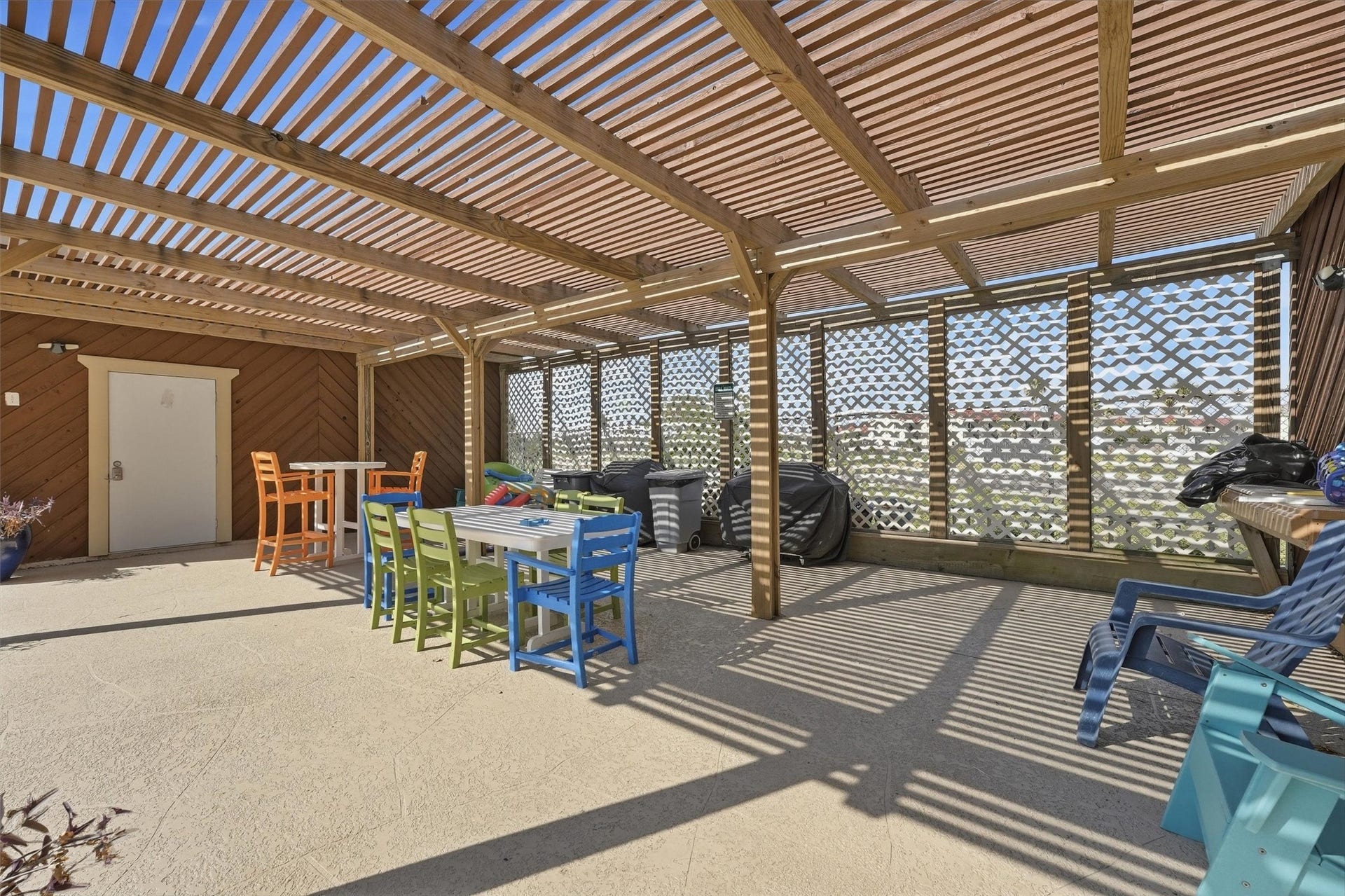7310 Seawall Boulevard, #1105, Galveston, TX 77551 Spacious covered patio with a wooden pergola, colorful seating, and a built-in grill area, perfect for outdoor entertaining.