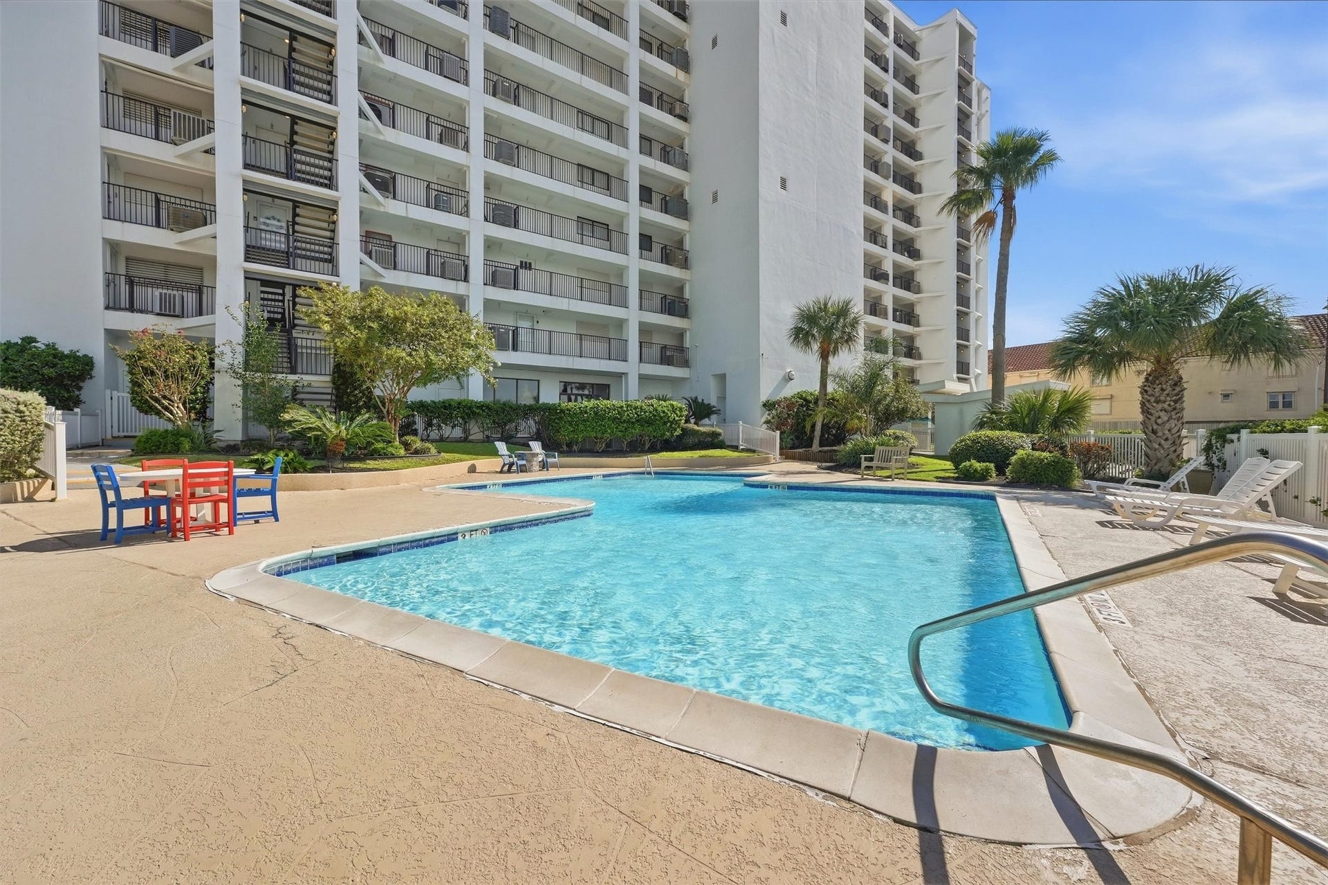 7310 Seawall Boulevard, #1105, Galveston, TX 77551 Enjoy resort-style living with this inviting outdoor pool area, surrounded by lush landscaping and ample seating, perfect for relaxation and entertaining.