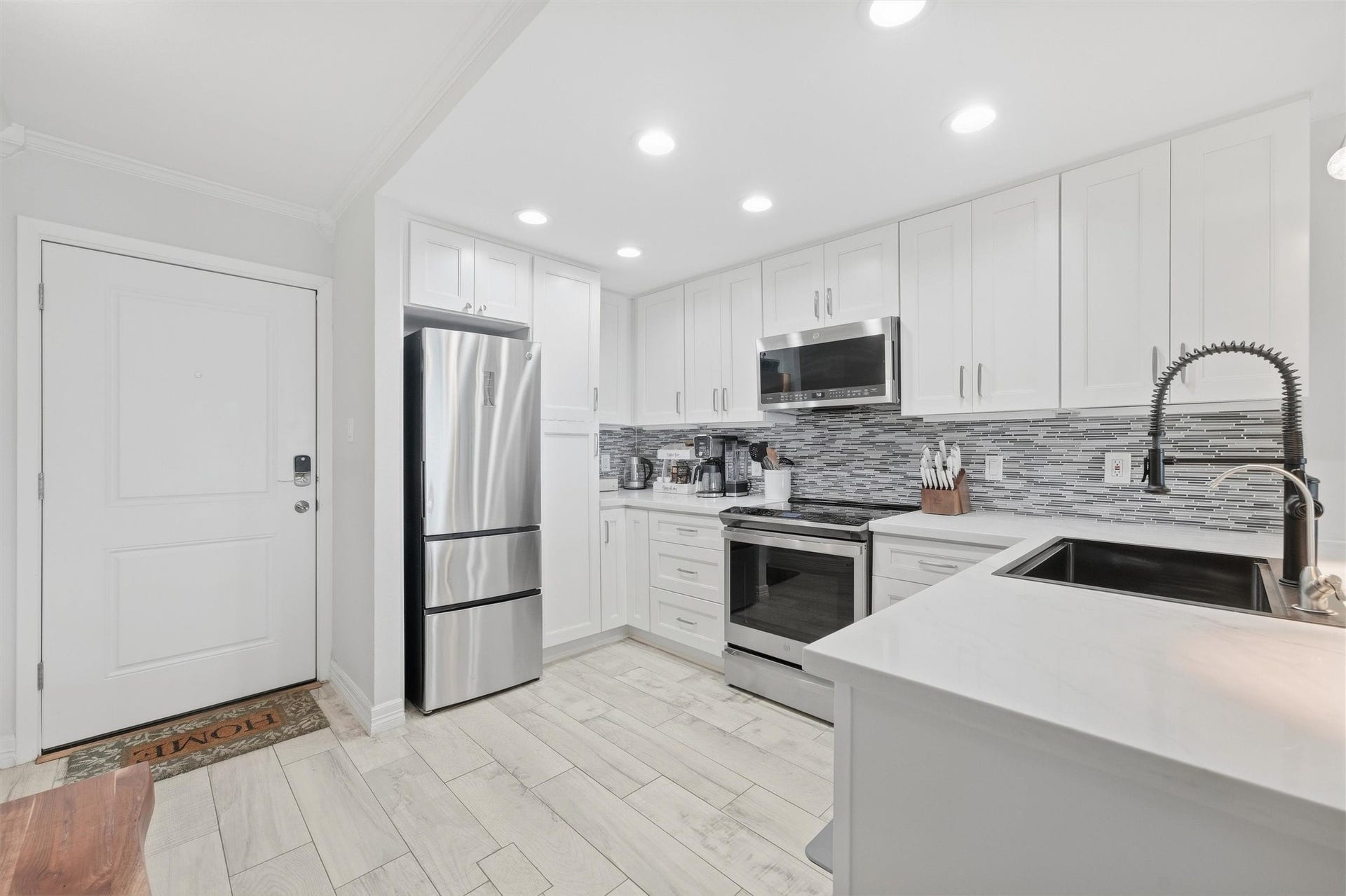 7310 Seawall Boulevard, #1105, Galveston, TX 77551 Modern kitchen with sleek white cabinetry, stainless steel appliances, and a stylish tile backsplash, offering a bright and inviting space.
