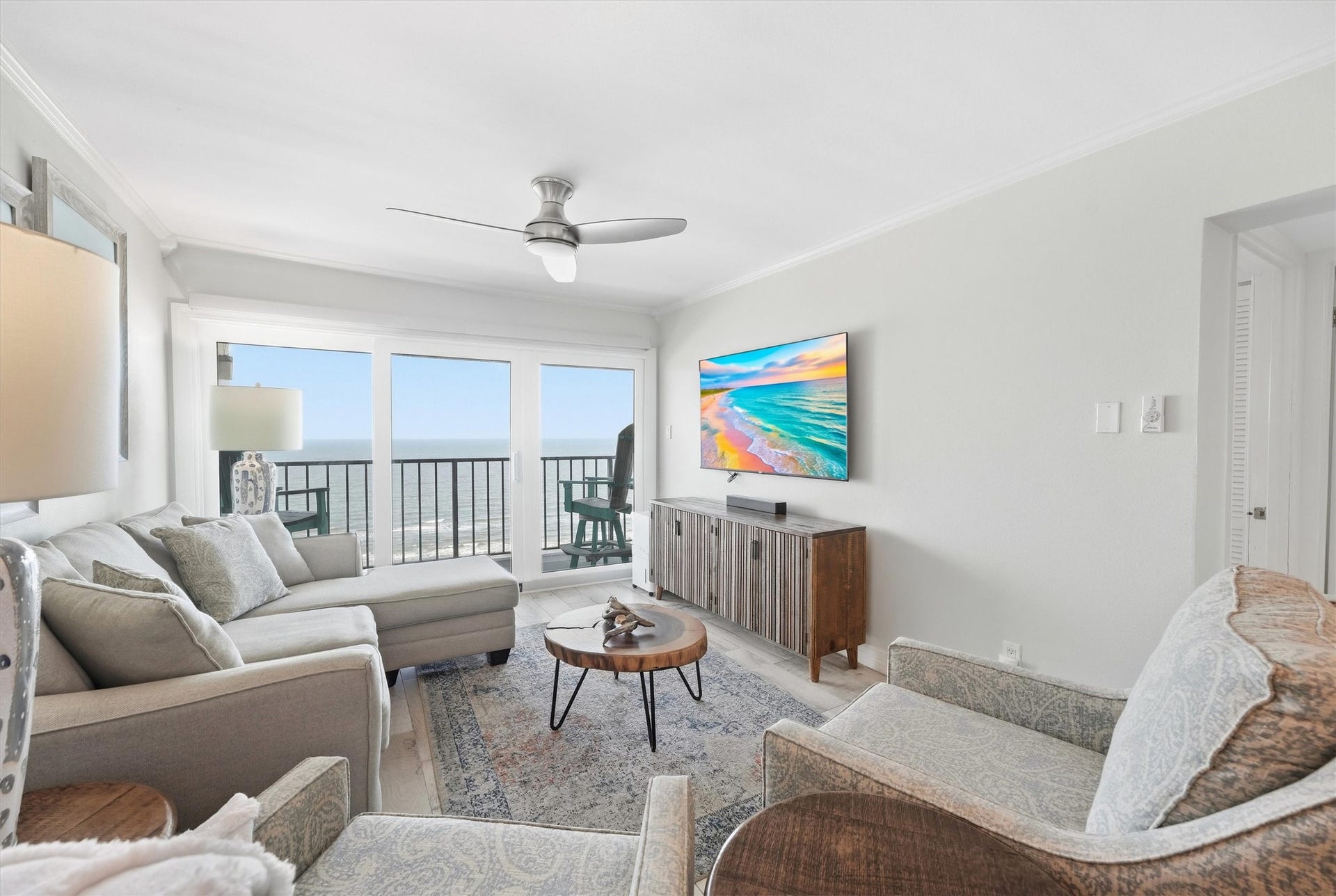 7310 Seawall Boulevard, #1105, Galveston, TX 77551 Bright and airy living room with ocean views, featuring a comfortable sectional, stylish armchairs, and a modern ceiling fan.