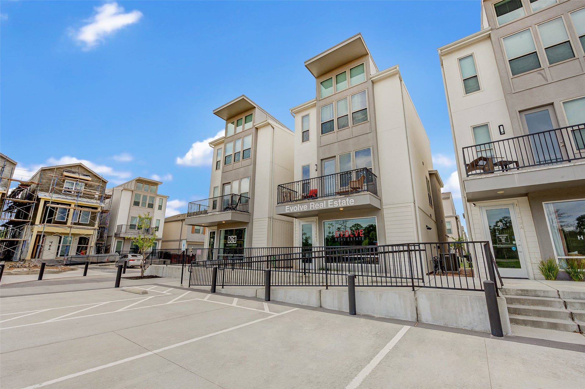 18732 Centro Main Street, Shenandoah, TX 77385 Modern multi-story townhouses with clean lines and large windows. The area features balconies, ample parking, and a clear blue sky, creating a welcoming and contemporary environment.