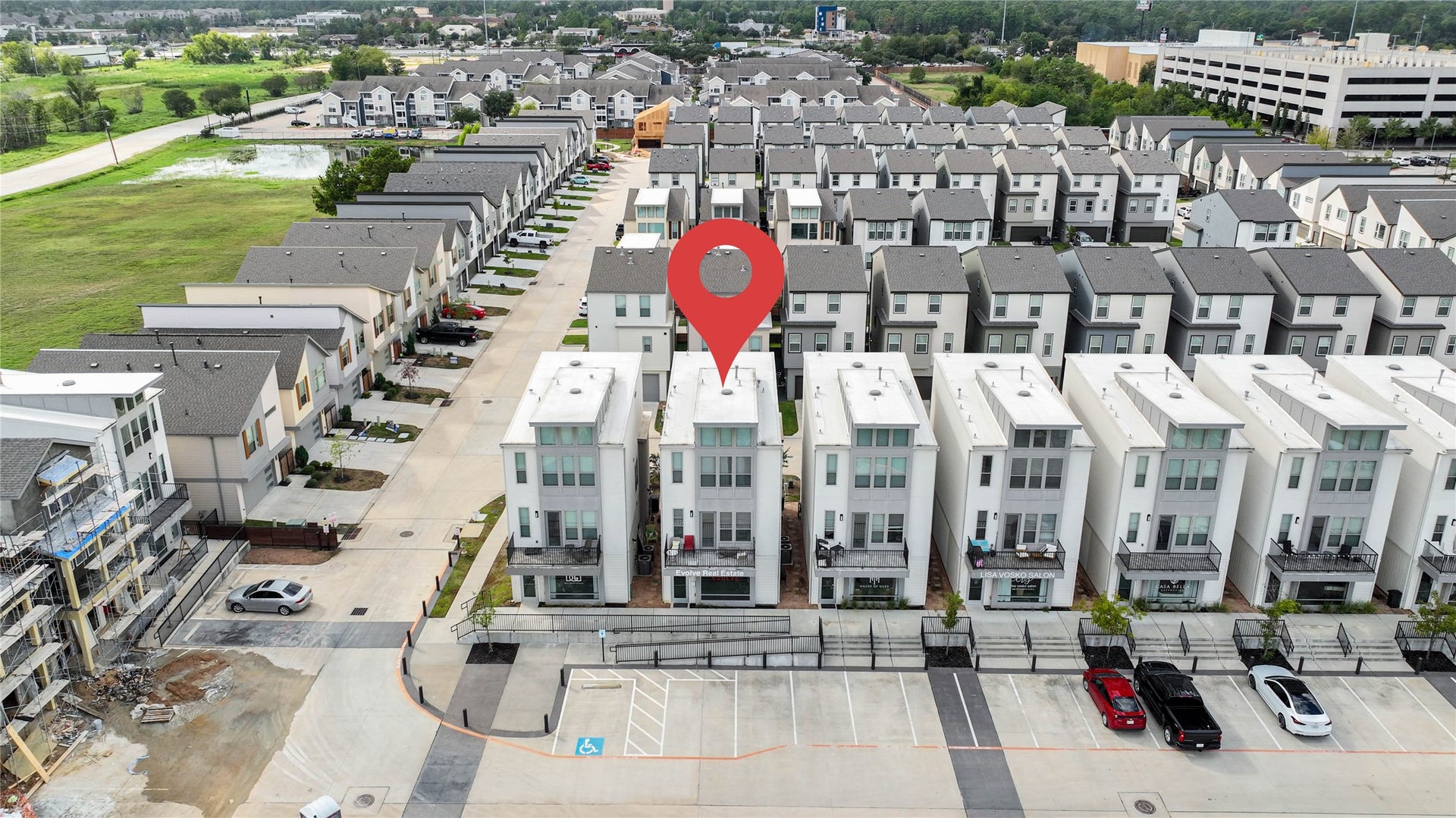 18732 Centro Main Street, Shenandoah, TX 77385 Modern row of white townhouses with clean lines and multiple stories, located in a well-organized residential community. The area appears spacious with parking and green surroundings, providing a suburban feel close to urban amenities.