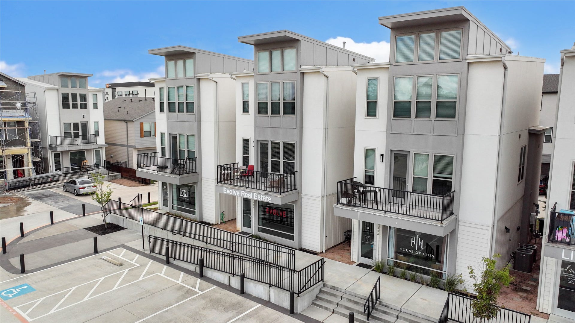 18732 Centro Main Street, Shenandoah, TX 77385 Modern townhouses with clean, contemporary architecture featuring three stories, large windows, and private balconies. The complex includes ground-level retail spaces and is situated in a well-maintained urban setting.