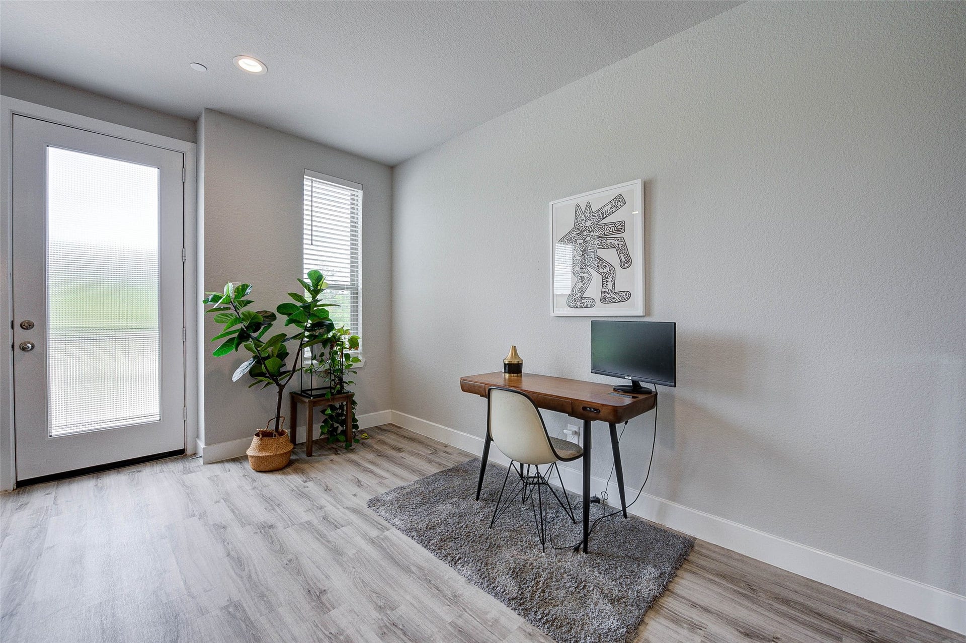 18732 Centro Main Street, Shenandoah, TX 77385 Bright and modern home office with light wood flooring, a sleek desk, and a stylish chair. Large windows and a glass door provide ample natural light, while indoor plants add a touch of greenery. Perfect for a productive work environment.