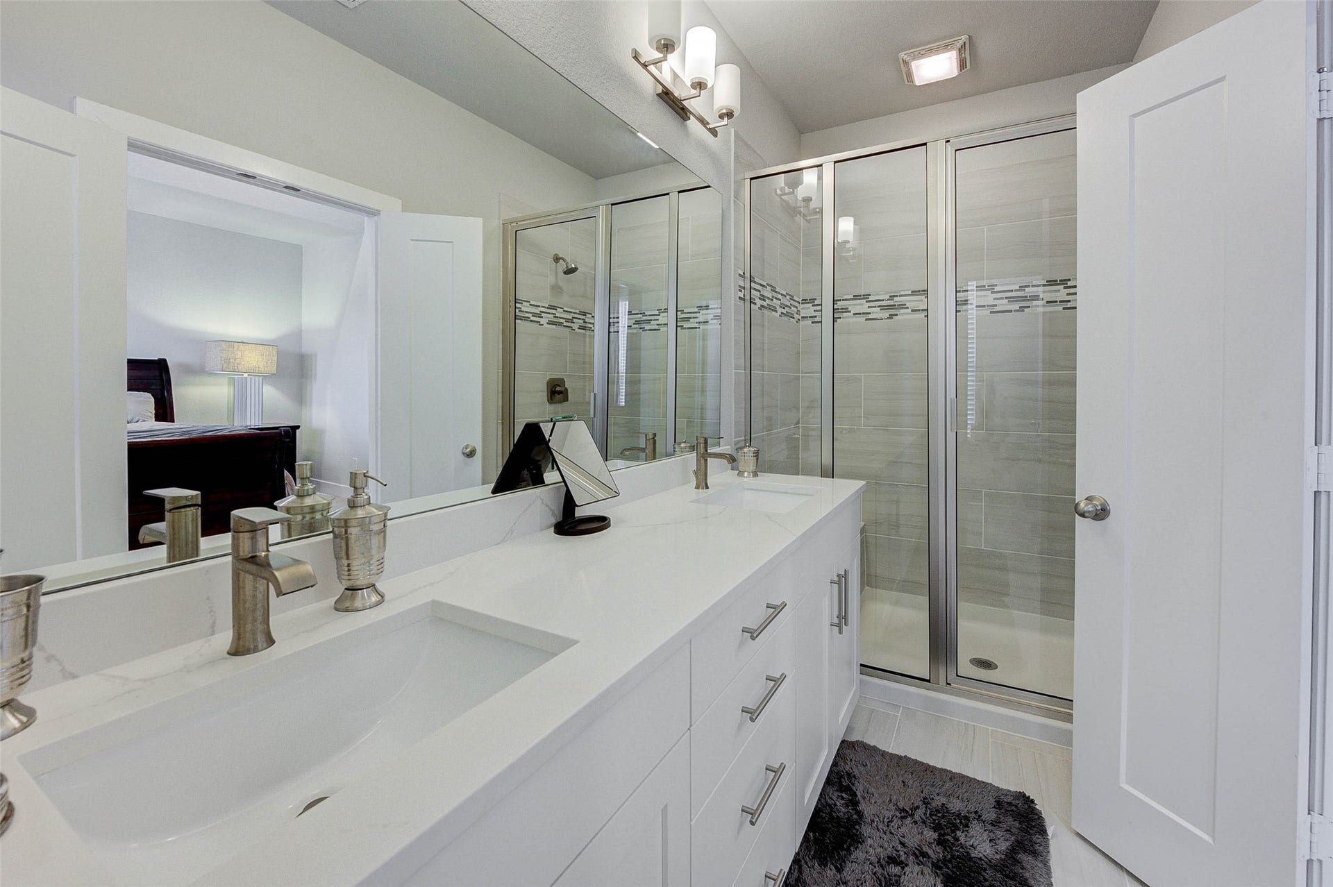 18732 Centro Main Street, Shenandoah, TX 77385 Modern bathroom with dual sinks, sleek fixtures, and a spacious glass-enclosed shower. Bright lighting and a neutral color palette create a clean, inviting atmosphere.