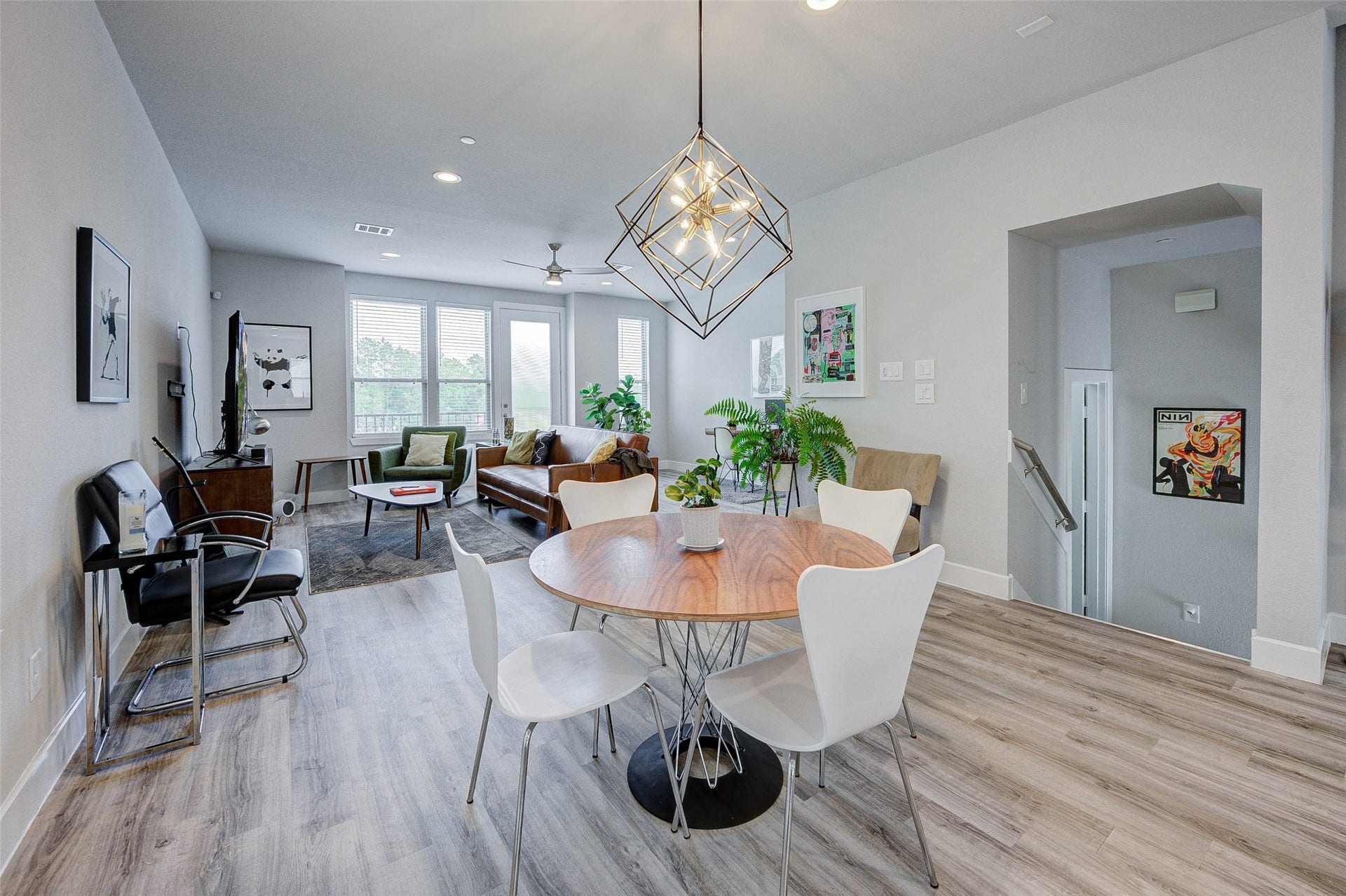 18732 Centro Main Street, Shenandoah, TX 77385 This modern living space features an open layout with a dining area, contemporary light fixture, and stylish decor. Natural light floods through large windows, highlighting the sleek flooring and comfortable seating area. Perfect for entertaining and relaxation.