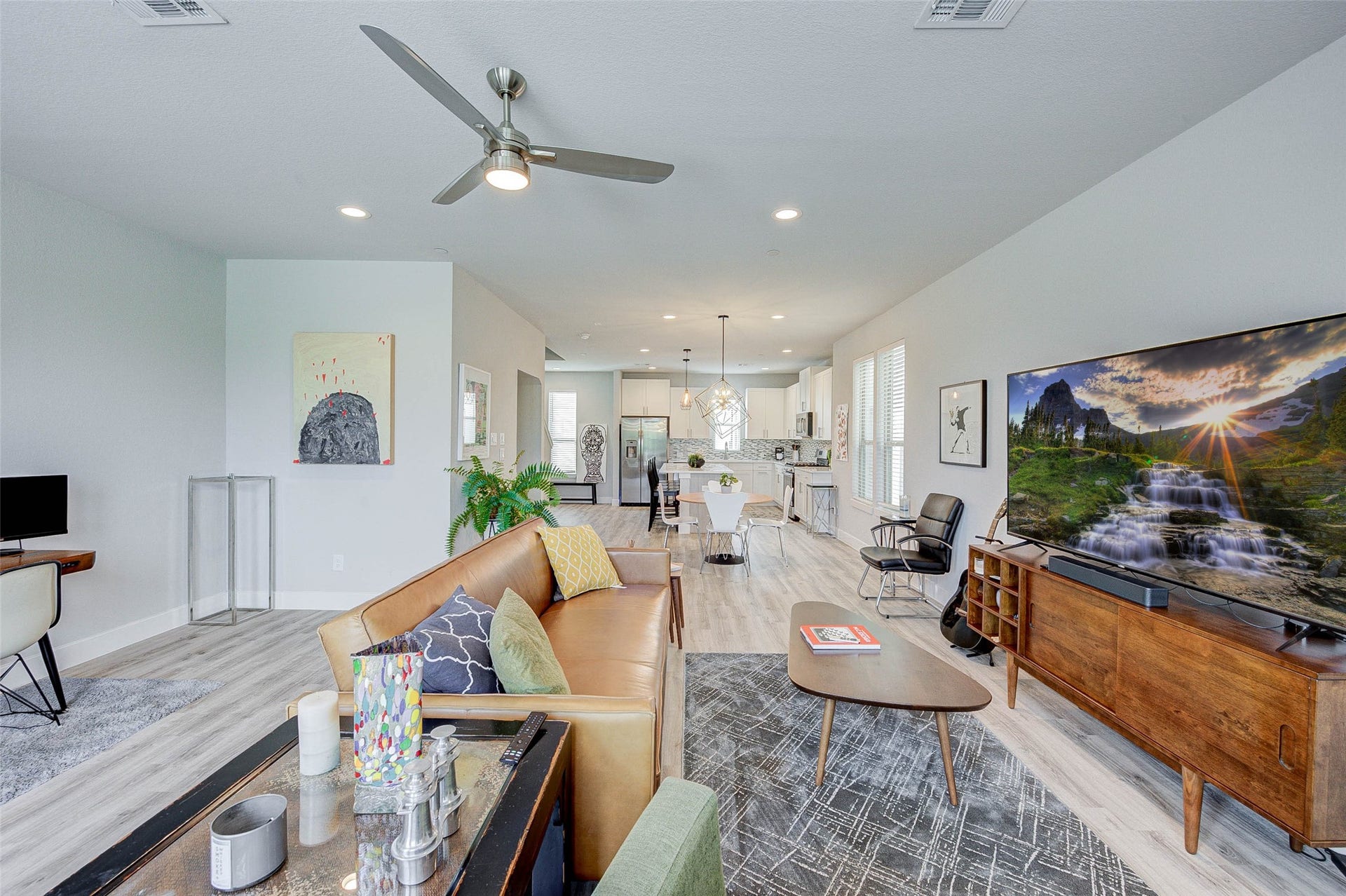 18732 Centro Main Street, Shenandoah, TX 77385 Spacious open-concept living area with modern design, featuring a cozy seating area, stylish decor, and a large TV. The room flows into a bright kitchen and dining space, highlighted by sleek appliances and contemporary lighting. Ideal for entertaining and family gatherings.