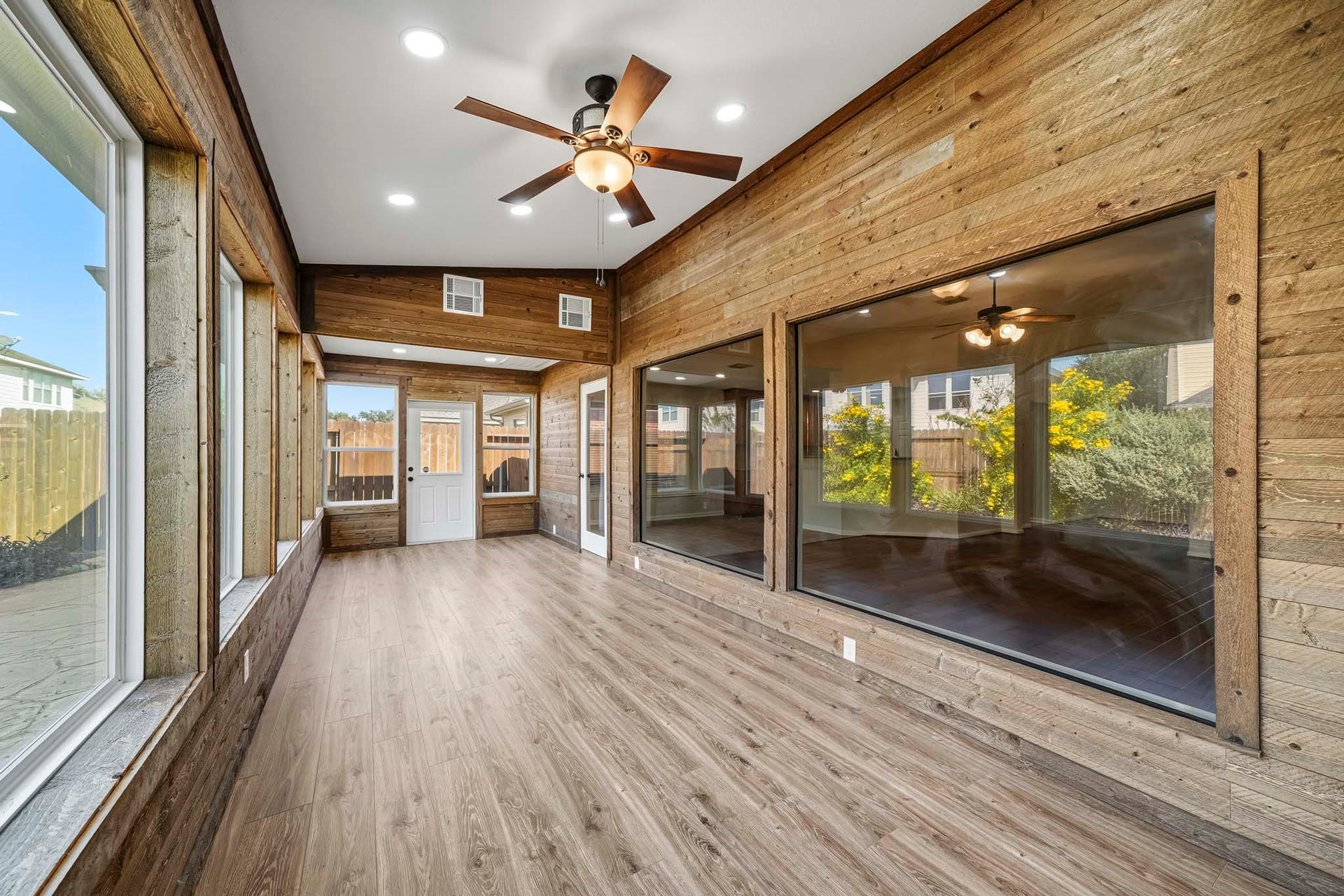 Sun room finished with wood walls and large windows adds warmth to this bonus space, creating a cozy and inviting atmosphere perfect for relaxation or entertaining.
