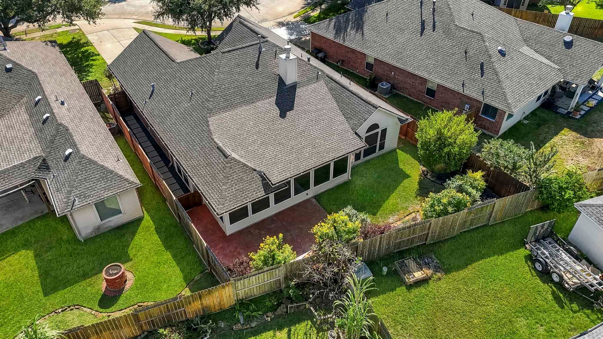 Aerial view of this one-story residence showcasing the full property layout, backyard, and surrounding neighborhood.