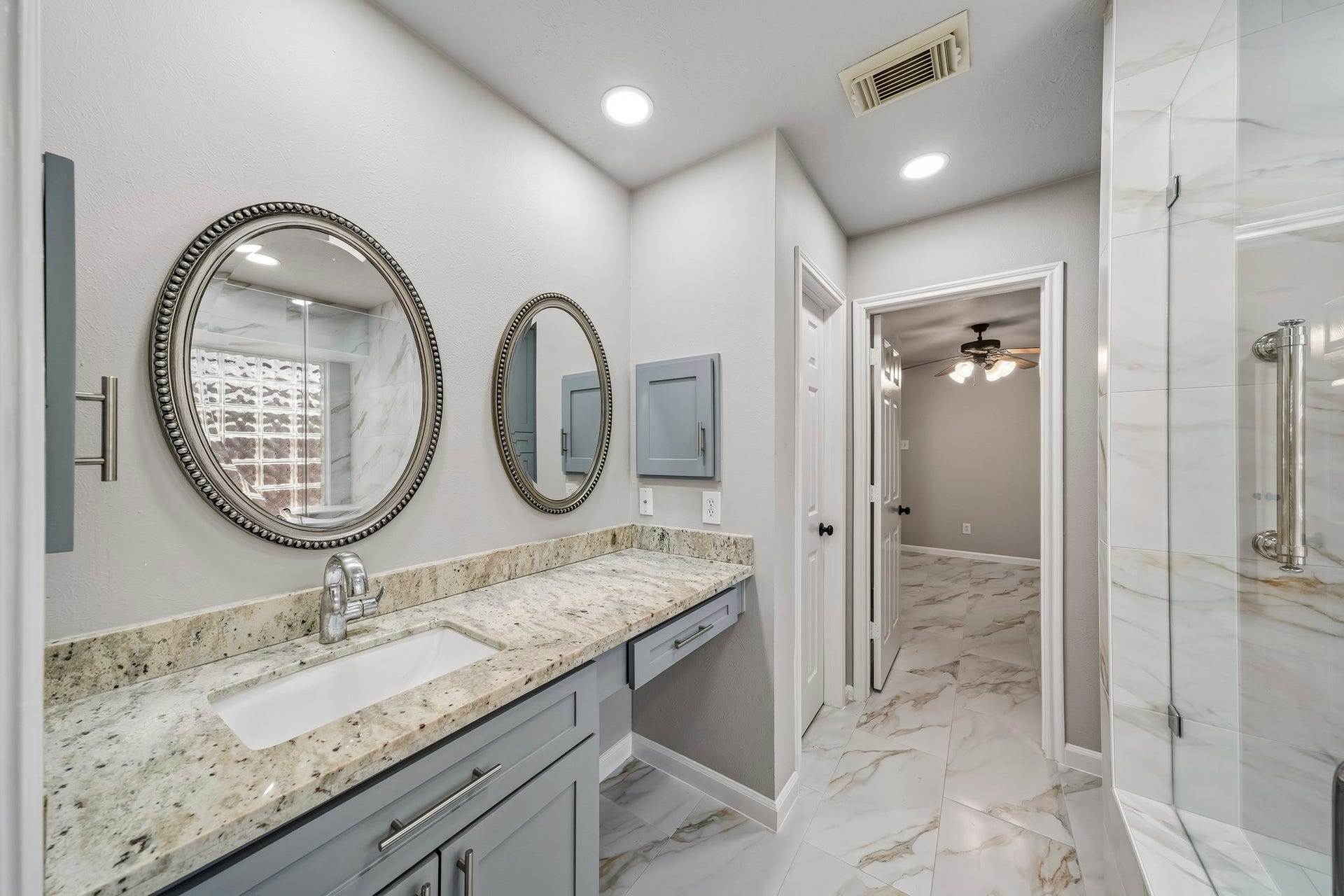 The space boasts an expansive vanity providing an abundance of smart storage solutions to keep your countertops clutter-free. Every detail has been thoughtfully selected, from the sleek, elegant hardware that adds a sophisticated touch to the clean lines and modern finishes that define the room's contemporary aesthetic.