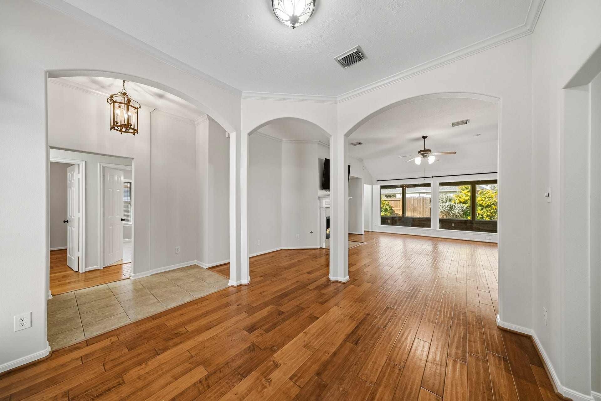 Expansive view from the dining room looking across the open-concept living space toward the sunroom, highlighted by a stunning wall of windows that floods the home with natural light.