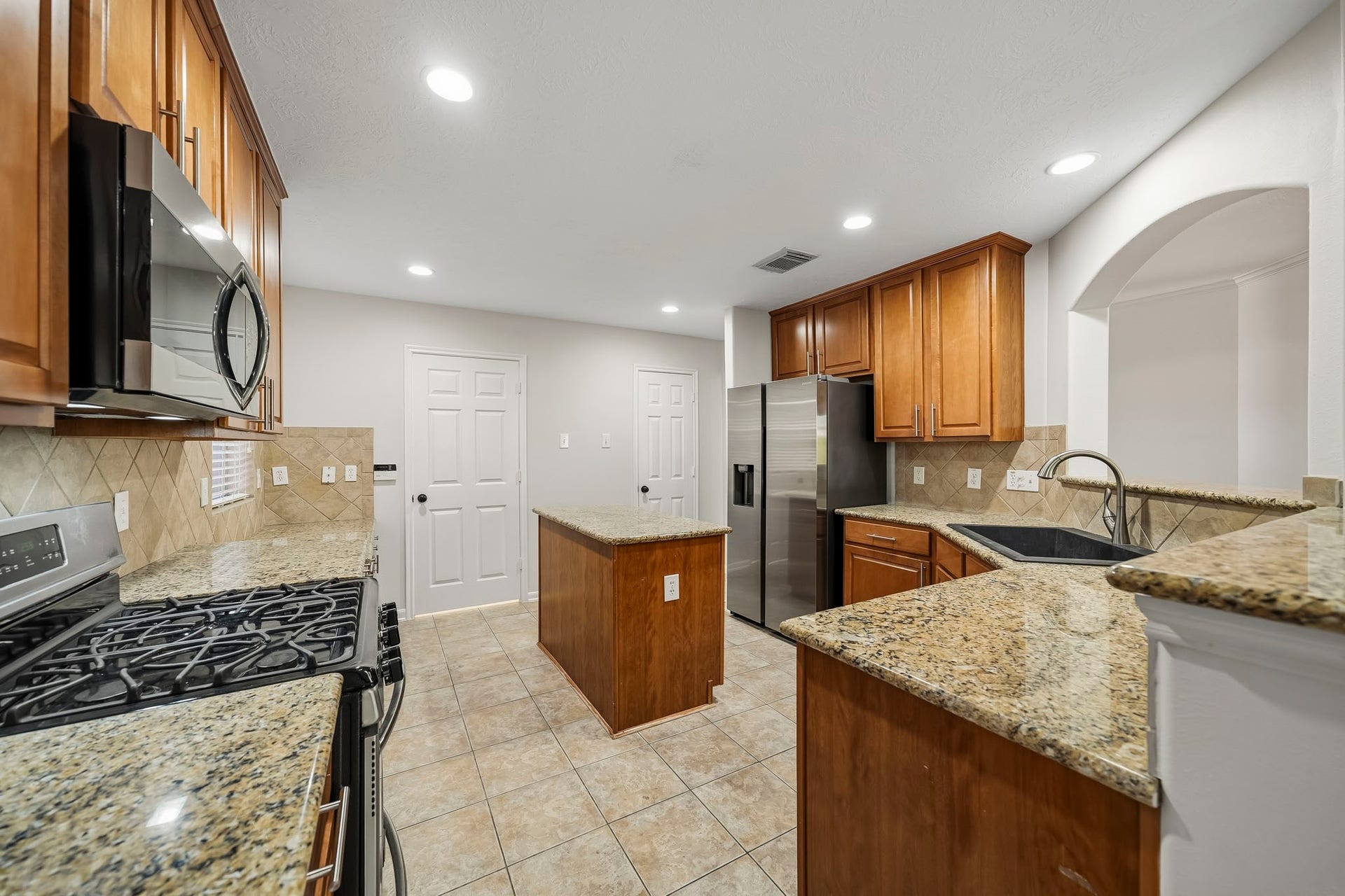 Lovely kitchen equipped with beautiful wood cabinetry, granite counters, and stainless steel appliances. This culinary space features high-end finishes and an open layout, perfect for both everyday meal preparation and entertaining guests.