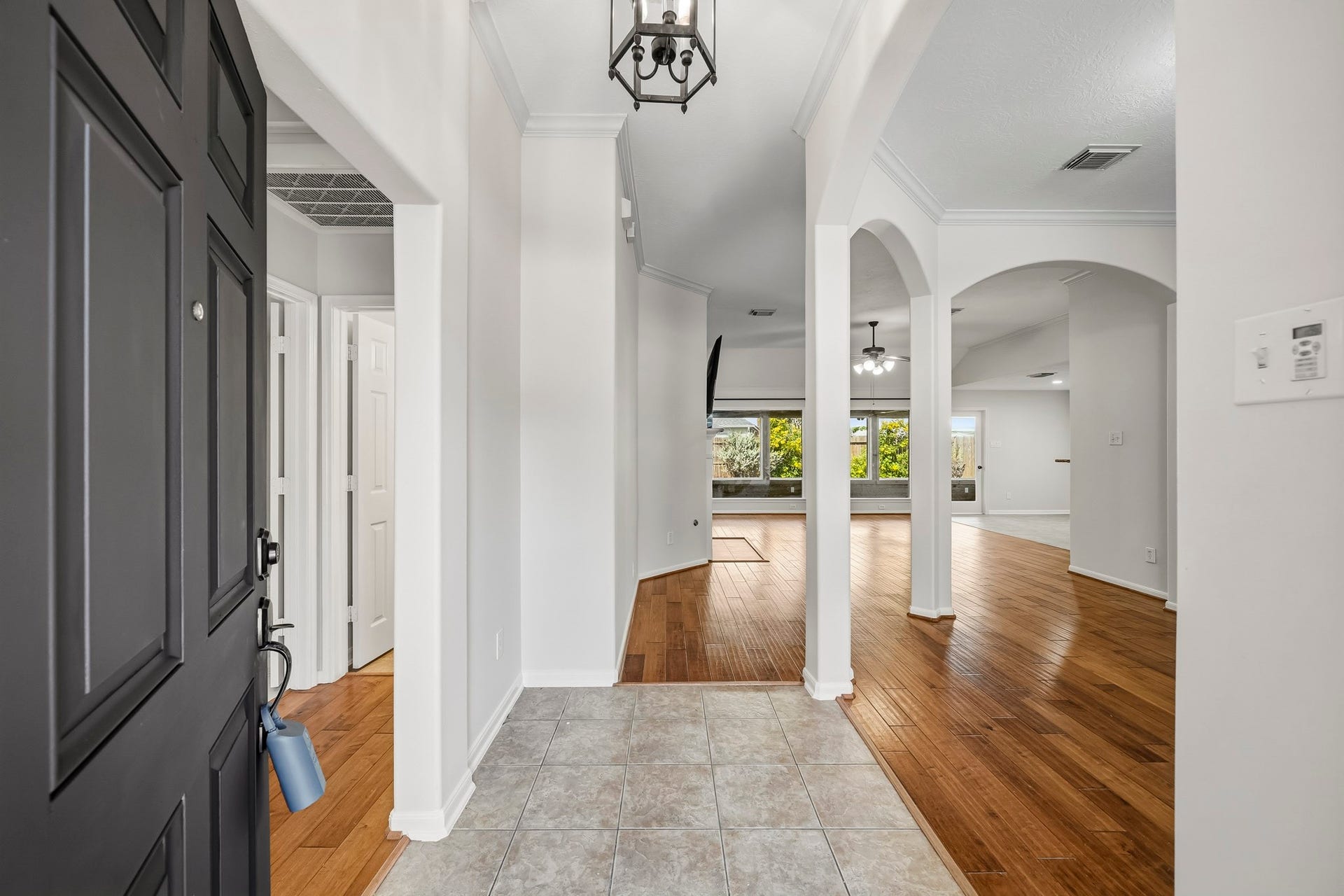 Formal entry featuring elegant architectural arches, a stunning chandelier, and gleaming hardwood floors, with a sophisticated dining room situated to the right.