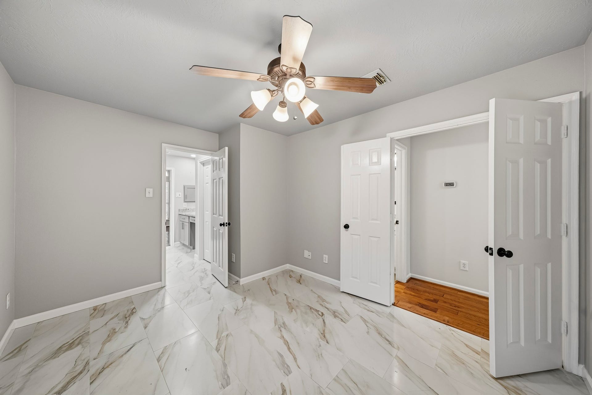 Sun-drenched home office featuring sophisticated double doors and an open layout that blends professional functionality with a seamless transition into the home's primary suite.