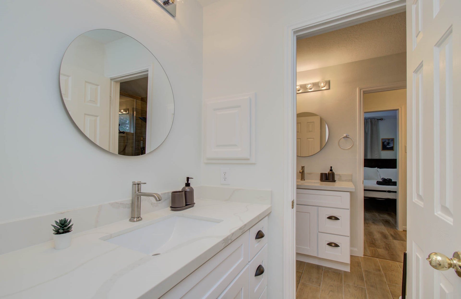 15627 Twisting Springs Drive, Cypress, TX 77433 Modern bathroom with sleek white cabinetry, elegant quartz countertops, and stylish round mirrors, offering a fresh and inviting atmosphere.