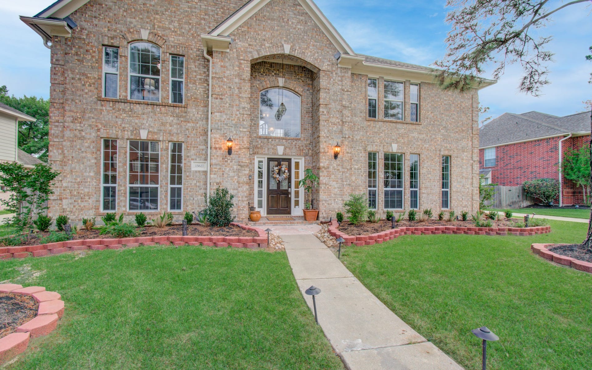 15627 Twisting Springs Drive, Cypress, TX 77433 Stately two-story brick home with elegant arched windows, manicured landscaping, and a welcoming front entrance.
