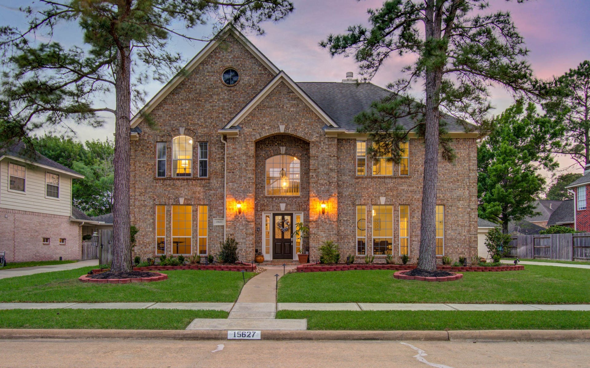 15627 Twisting Springs Drive, Cypress, TX 77433 Stunning two-story brick home with elegant arched entryway, large windows, and beautiful landscaping, framed by mature trees.