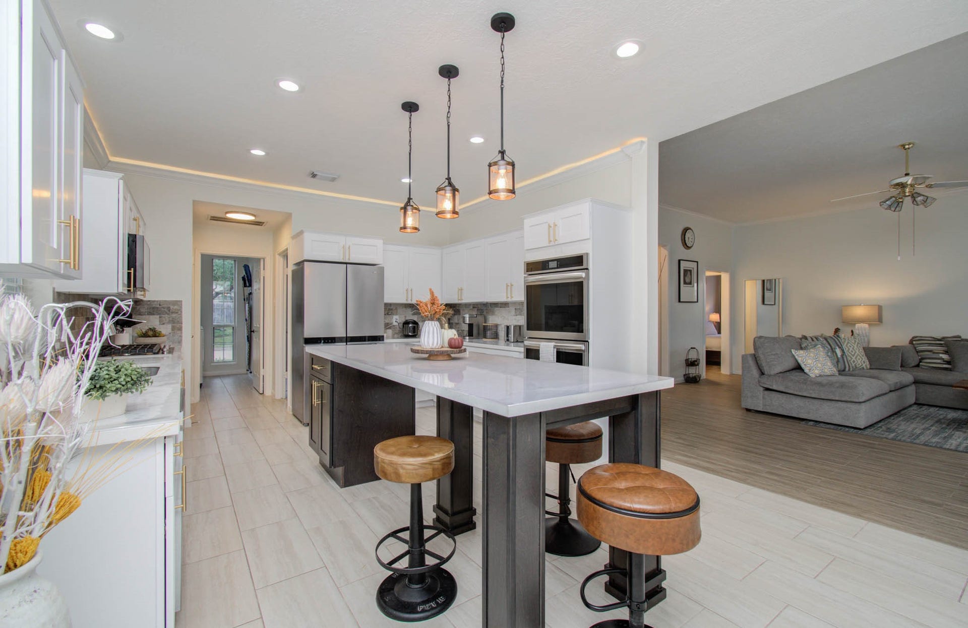 15627 Twisting Springs Drive, Cypress, TX 77433 Spacious modern kitchen with sleek white cabinetry, stainless steel appliances, and a large island with stylish pendant lighting, seamlessly flowing into a cozy living area.