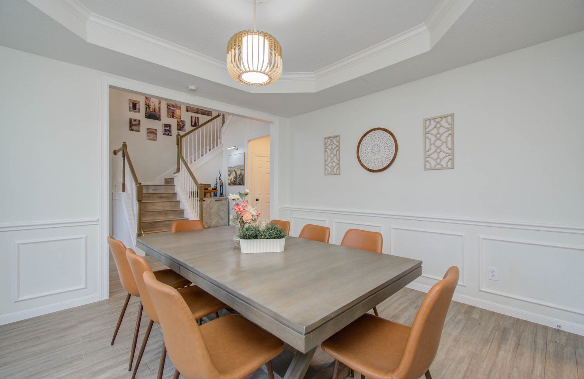 15627 Twisting Springs Drive, Cypress, TX 77433 Elegant dining area with a modern table, stylish leather chairs, and a chic light fixture, leading to a staircase with charming wall decor.