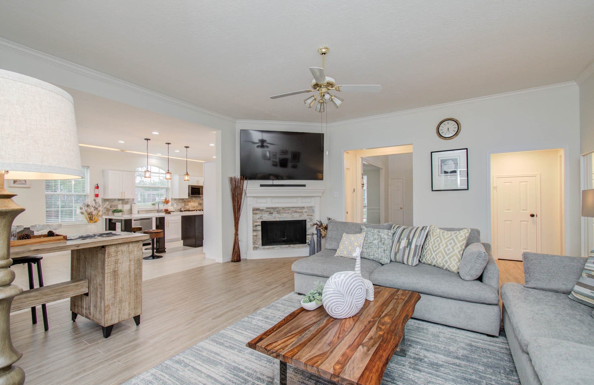 15627 Twisting Springs Drive, Cypress, TX 77433 Spacious living area with a cozy fireplace, modern ceiling fan, and an open layout connecting to the kitchen. Natural light enhances the neutral tones and stylish decor, creating an inviting and comfortable atmosphere.
