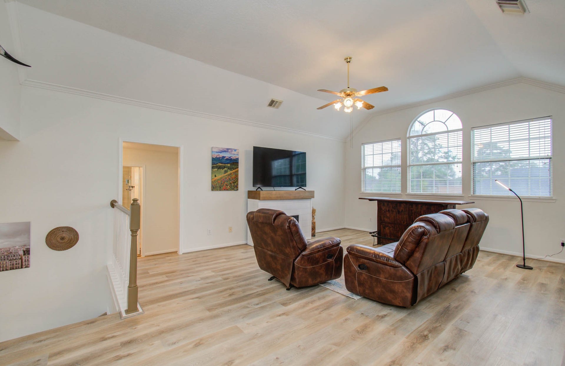 15627 Twisting Springs Drive, Cypress, TX 77433 Bright and spacious living area with vaulted ceilings, large arched windows, and stylish wood flooring, perfect for relaxation and entertainment.