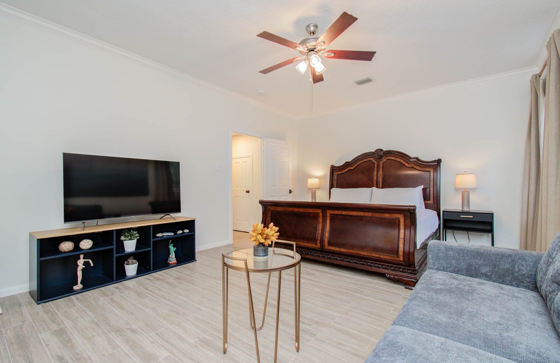 15627 Twisting Springs Drive, Cypress, TX 77433 Spacious bedroom featuring a luxurious wooden bed, modern ceiling fan, and a cozy seating area, complemented by a large TV and stylish decor for ultimate comfort.