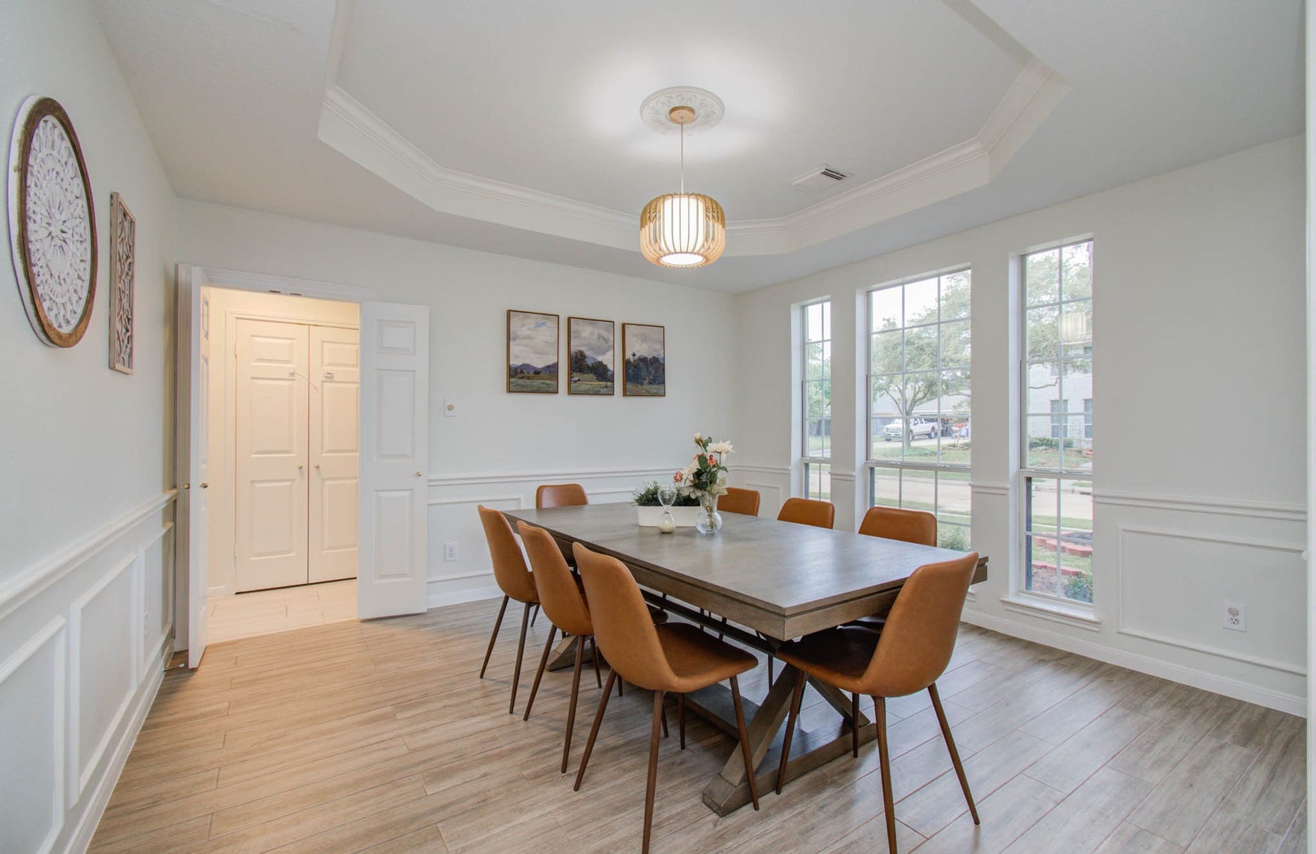 15627 Twisting Springs Drive, Cypress, TX 77433 Elegant dining room with a coffered ceiling and large windows, offering abundant natural light. The space features a stylish pendant light fixture, modern wood flooring, and wainscoting for a touch of sophistication.