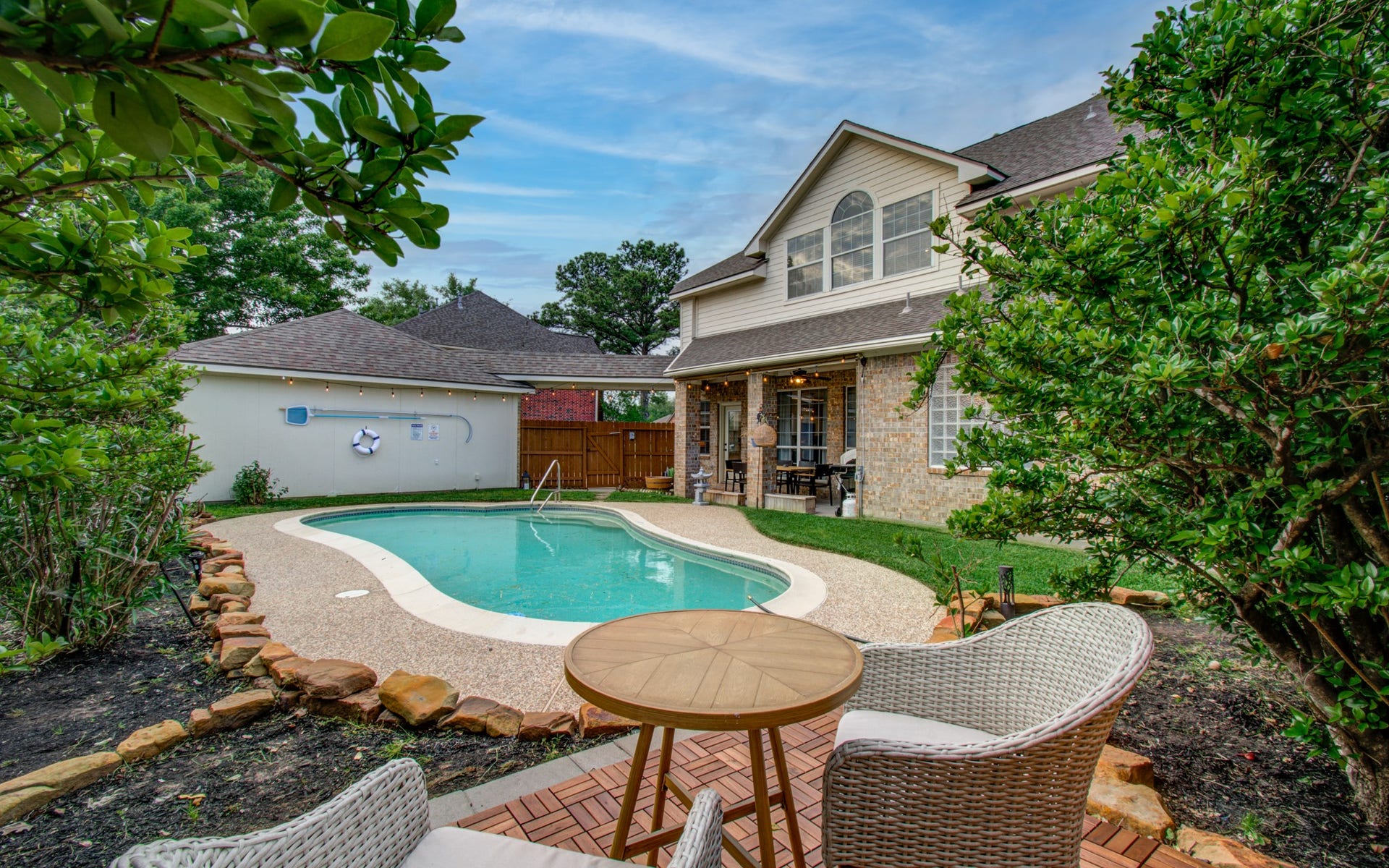 15627 Twisting Springs Drive, Cypress, TX 77433 Charming backyard oasis with a sparkling pool, cozy seating area, and lush greenery, perfect for relaxation and entertaining.