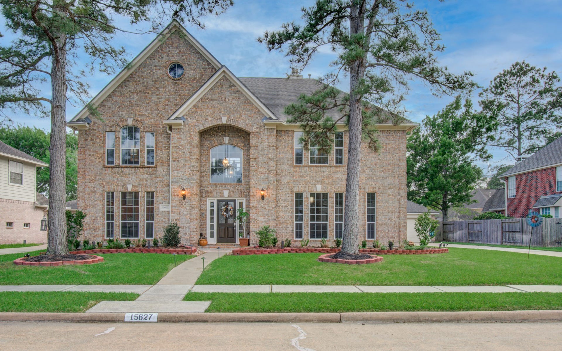 15627 Twisting Springs Drive, Cypress, TX 77433 Stately brick home with a grand entrance, large windows, and beautifully landscaped front yard framed by mature trees.