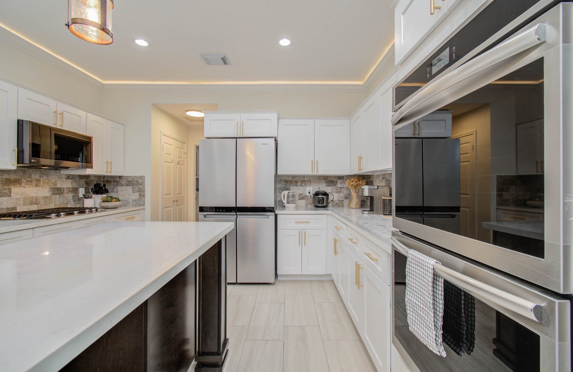 15627 Twisting Springs Drive, Cypress, TX 77433 Elegant kitchen featuring modern stainless steel appliances, white cabinetry with gold accents, and a spacious island for entertaining.