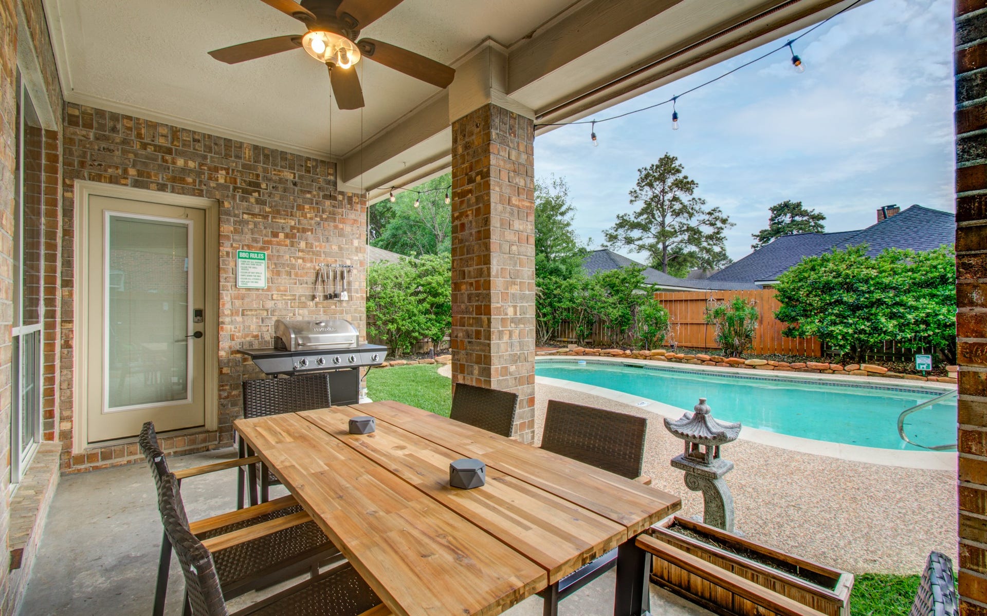 15627 Twisting Springs Drive, Cypress, TX 77433 Charming outdoor patio with a ceiling fan and grill, perfect for entertaining, overlooks a serene pool and lush landscaping.