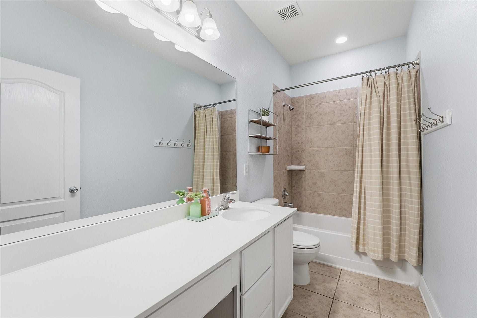 3502 Saxton Green Rd Road, Pearland, TX 77584 Full guest bathroom with a long vanity, neutral finishes and a tiled tub/shower surround.