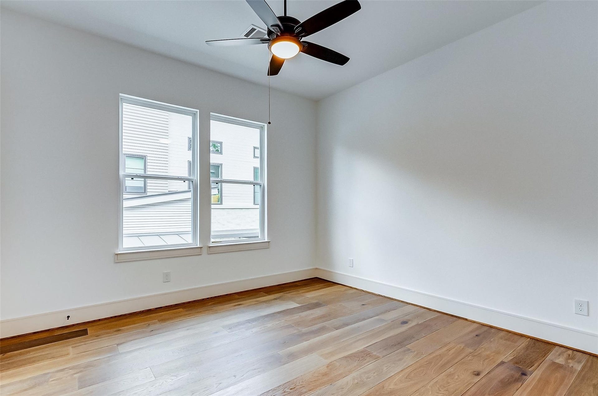 605 E 26th A Street, Houston, TX 77008 Bright and airy room with sleek hardwood flooring, modern ceiling fan, and large windows inviting natural light.