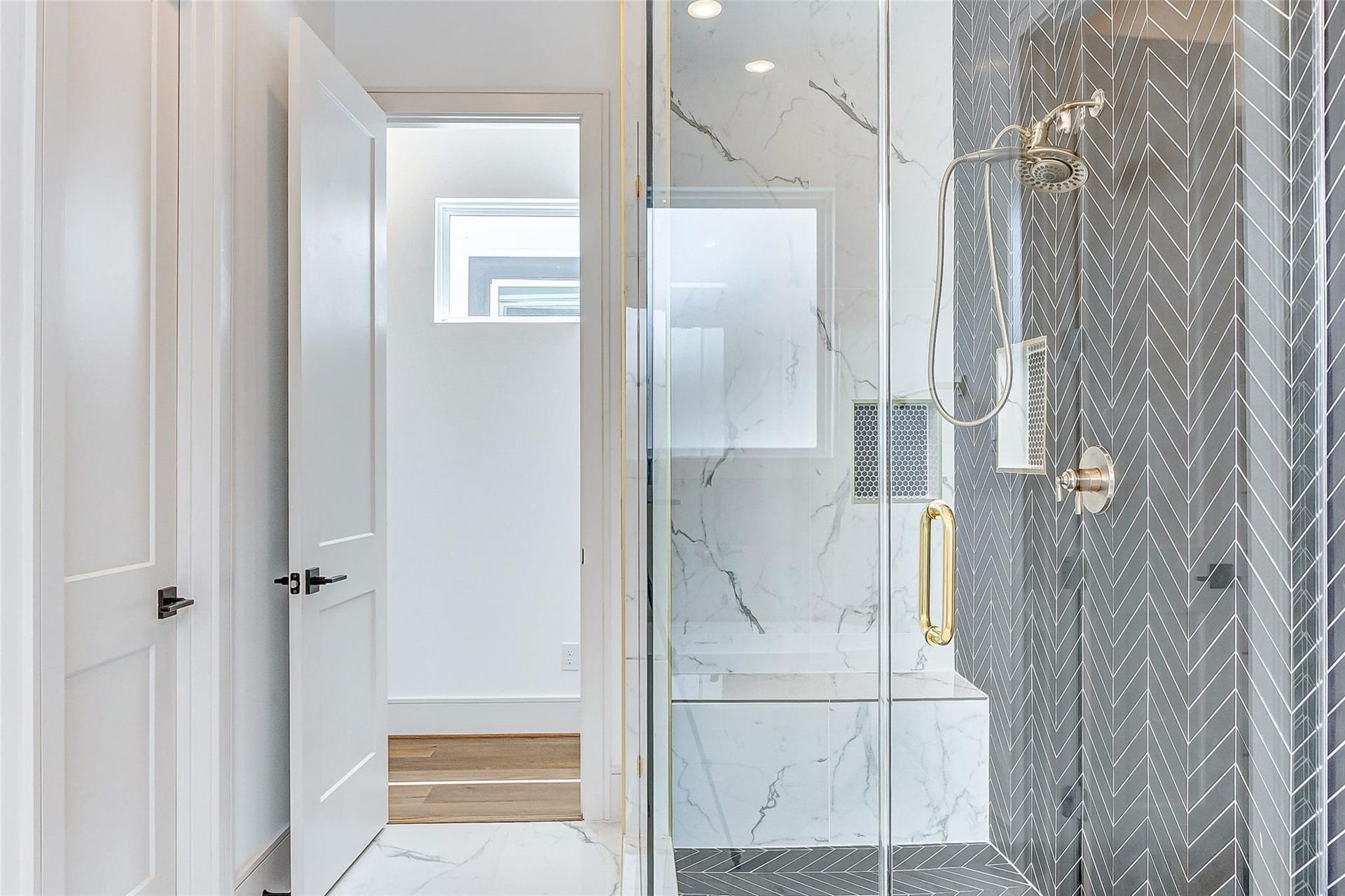 605 E 26th A Street, Houston, TX 77008 Frameless glass enclosed standing shower with herringbone tile and modern brass hardware.