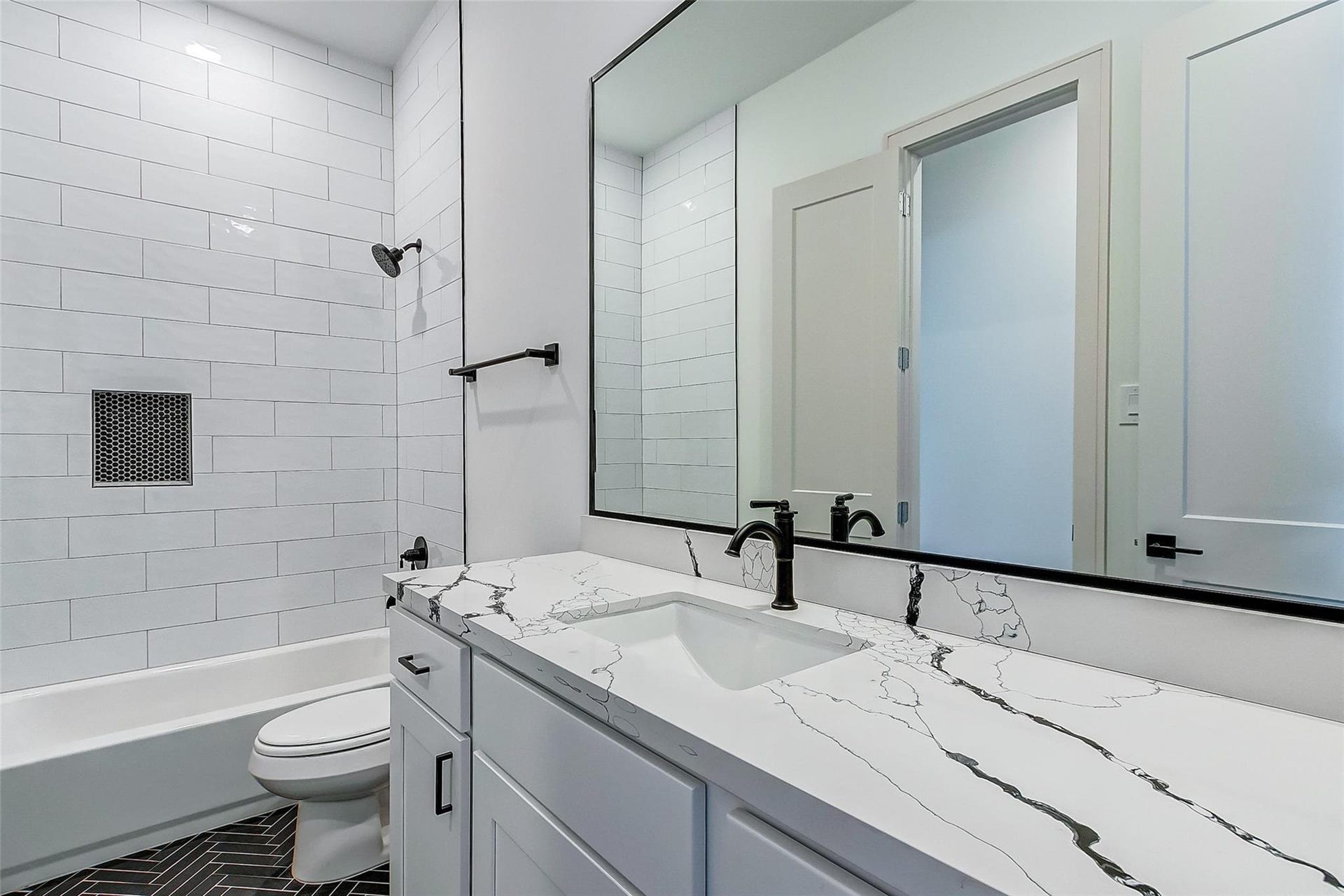605 E 26th A Street, Houston, TX 77008 Elegant bathroom featuring a sleek black and white design, with a spacious countertop, modern fixtures, and a stylish tiled shower for a touch of luxury.