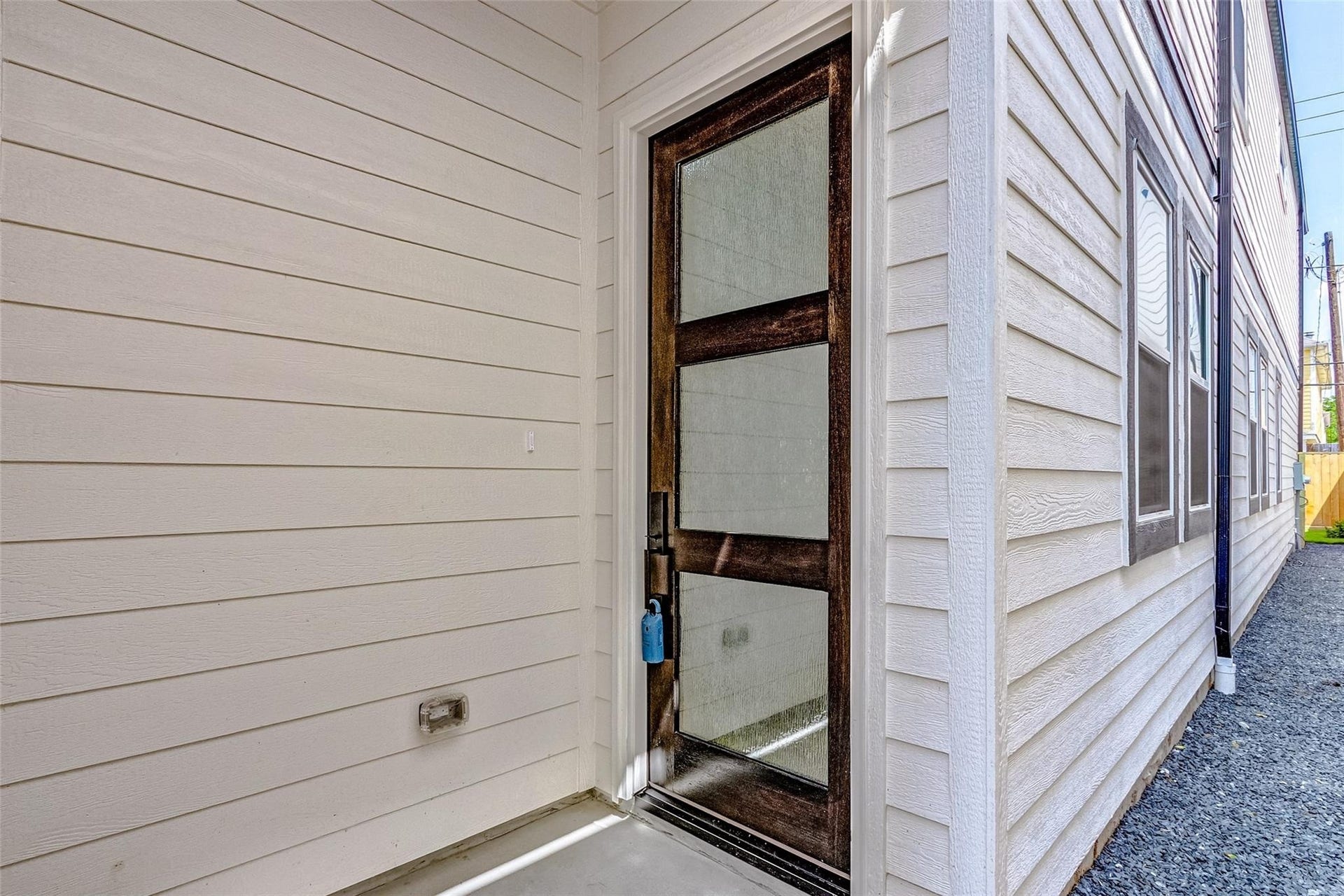 605 E 26th A Street, Houston, TX 77008 Inviting entryway featuring a sleek glass-paneled door, complemented by hardy plank siding, offering a welcoming and contemporary feel.