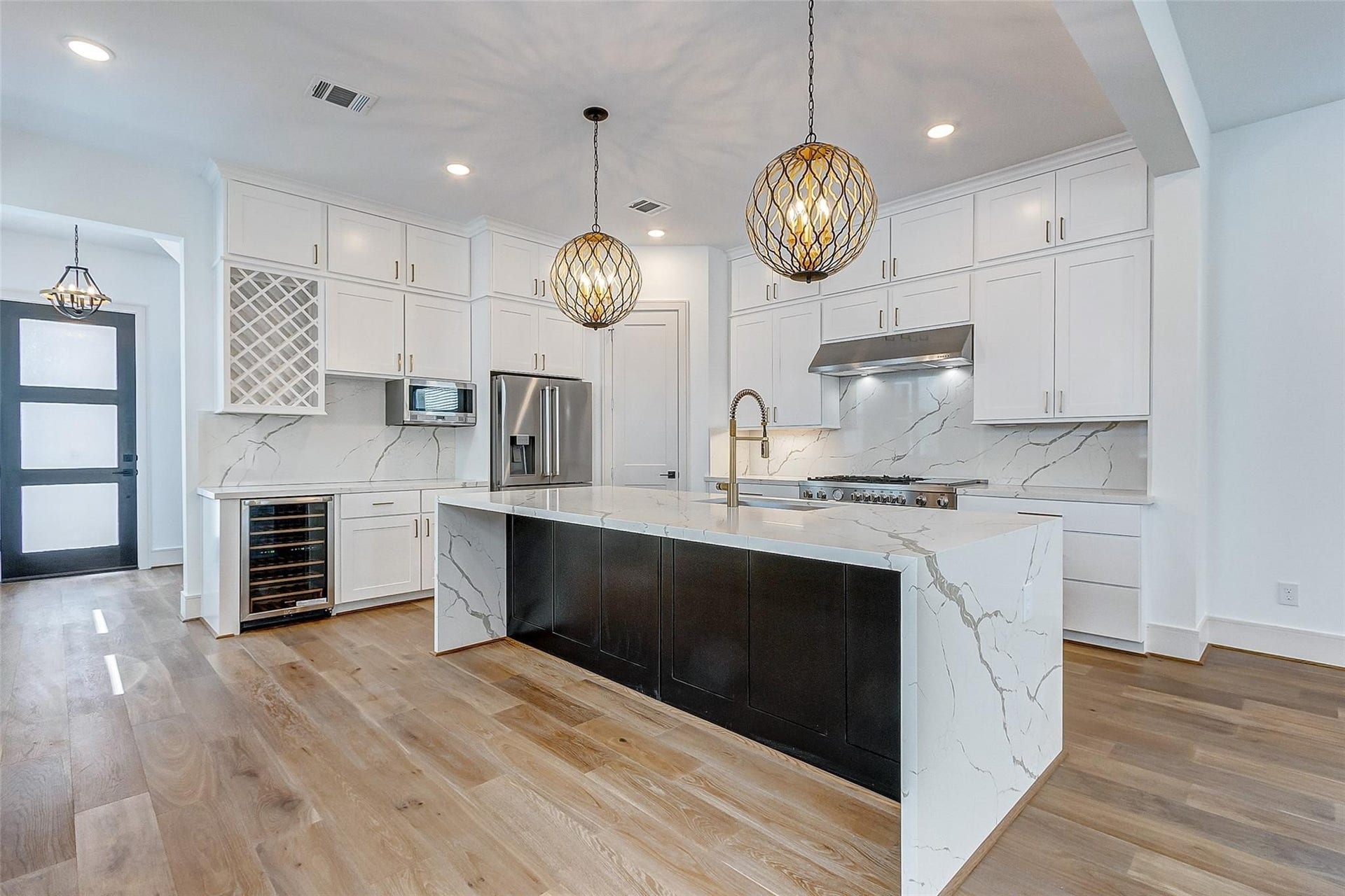 605 E 26th A Street, Houston, TX 77008 Experience luxury in this modern kitchen featuring a spacious island with elegant waterfall countertops and statement pendant lighting. High-end stainless steel appliances, a sleek wine cooler, and ample cabinetry provide style and functionality.