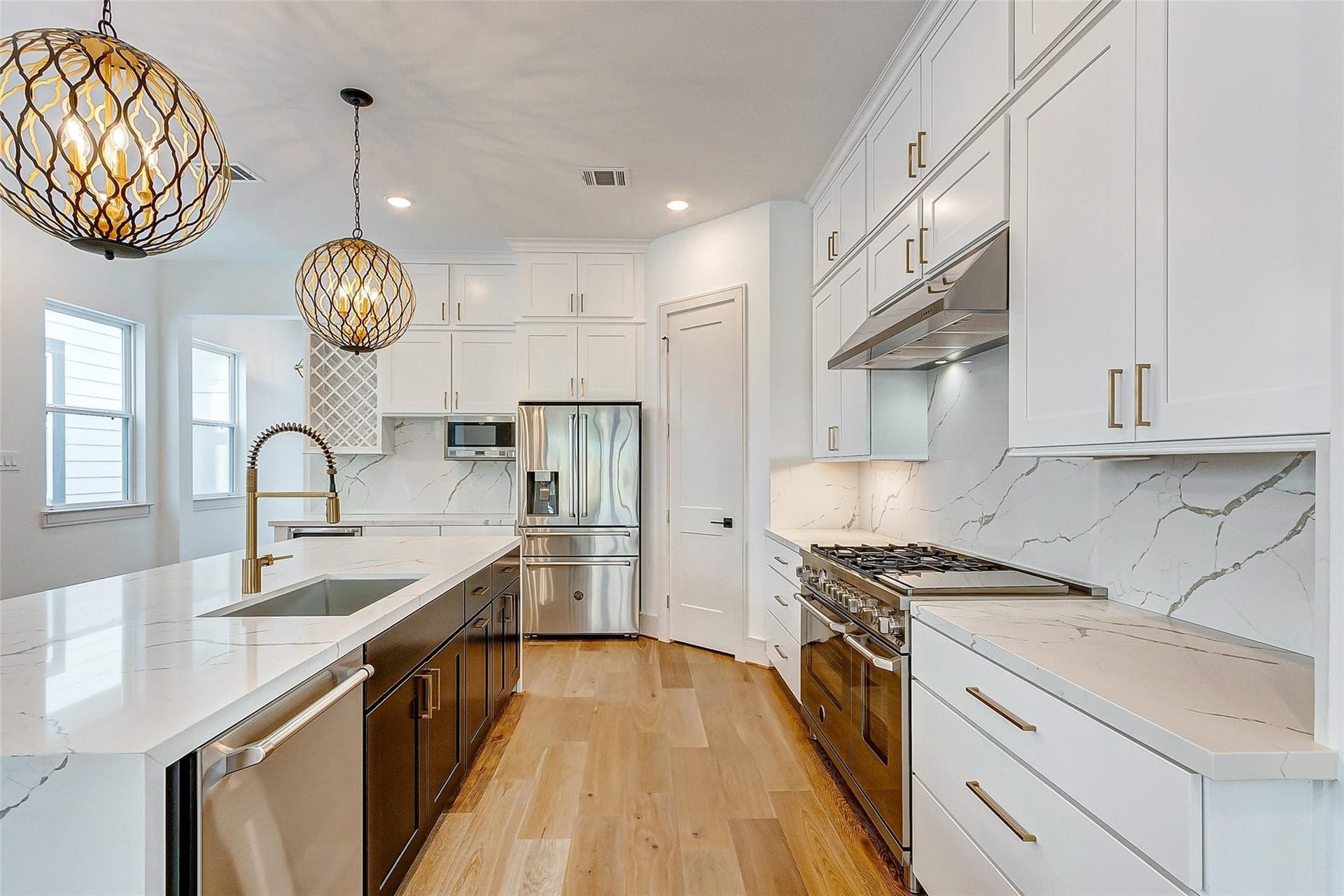 605 E 26th A Street, Houston, TX 77008 Stunning chefs kitchen showcasing sleek white cabinetry, elegant quartz countertops, and state-of-the-art stainless steel high end appliances. The space is illuminated by stylish pendant lighting, complementing the warm wood flooring and sophisticated design.