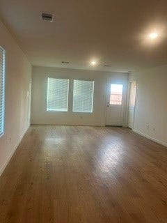 Spacious living area with abundant natural light, featuring hardwood floors, recessed lighting, and large windows.