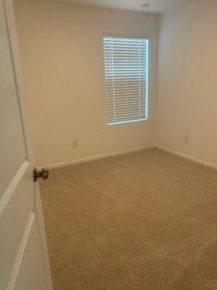 Cozy bedroom with soft carpeting and natural light streaming through a window with blinds, offering a clean and inviting space.