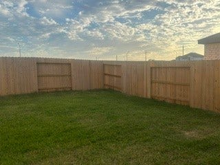 Spacious backyard with lush green grass and a sturdy wooden fence, perfect for relaxation and outdoor activities.
