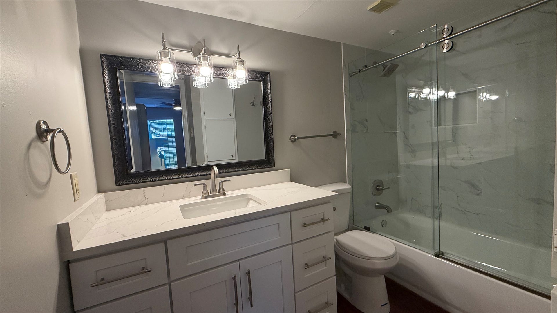 2250 Bering Drive, #40, Houston, TX 77057 Updated bathroom featuring a spacious vanity, decorative mirror, modern lighting, and glass-enclosed tub/shower combination.