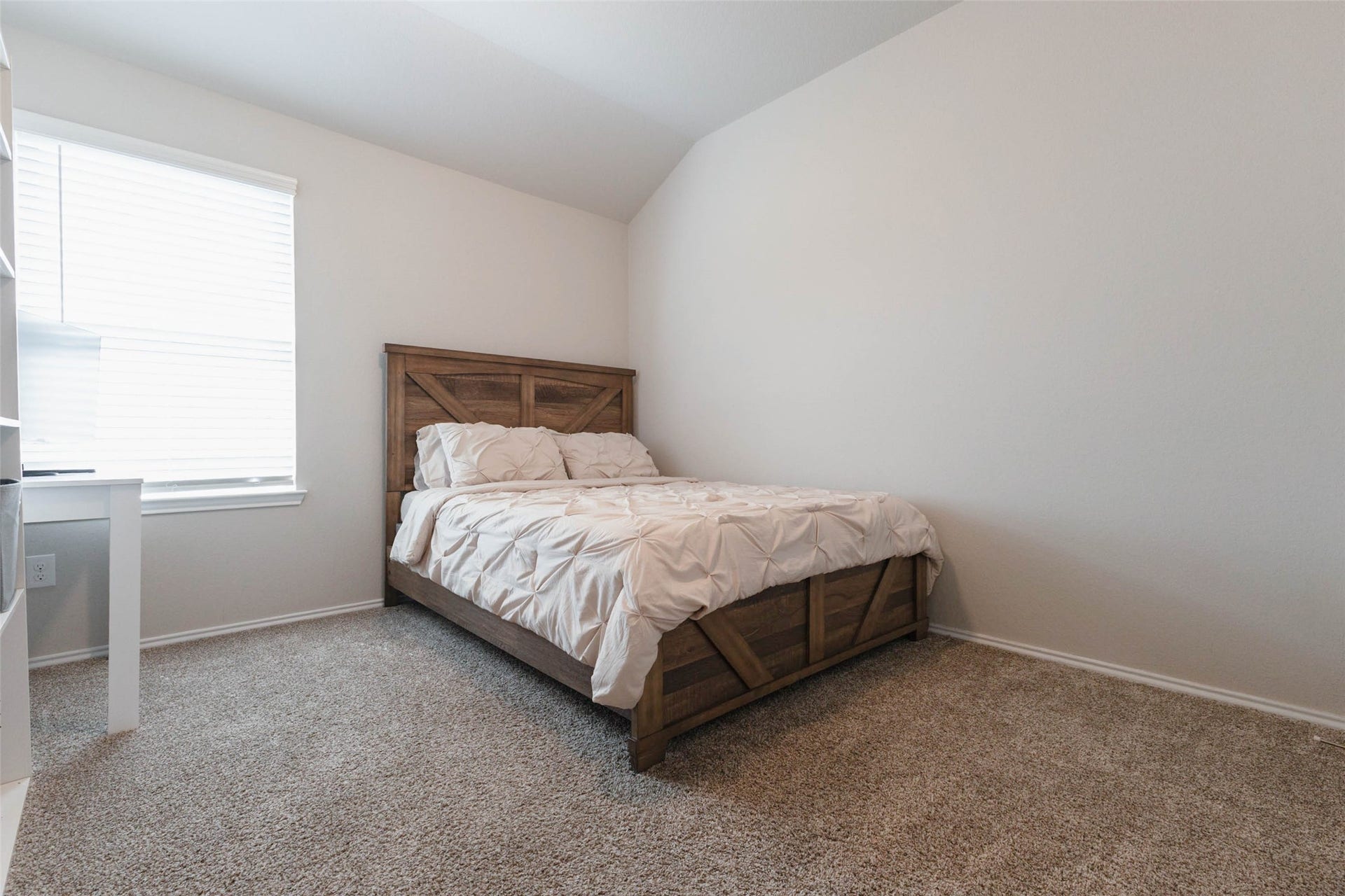 15303 Dinnet Berm Drive, Humble, TX 77346 Guest bedroom number two offers cozy carpeting, calm light toned walls, and a vaulted ceiling that adds a sense of height. A large window brings in a warm glow and gives the room a cheerful, open feel.