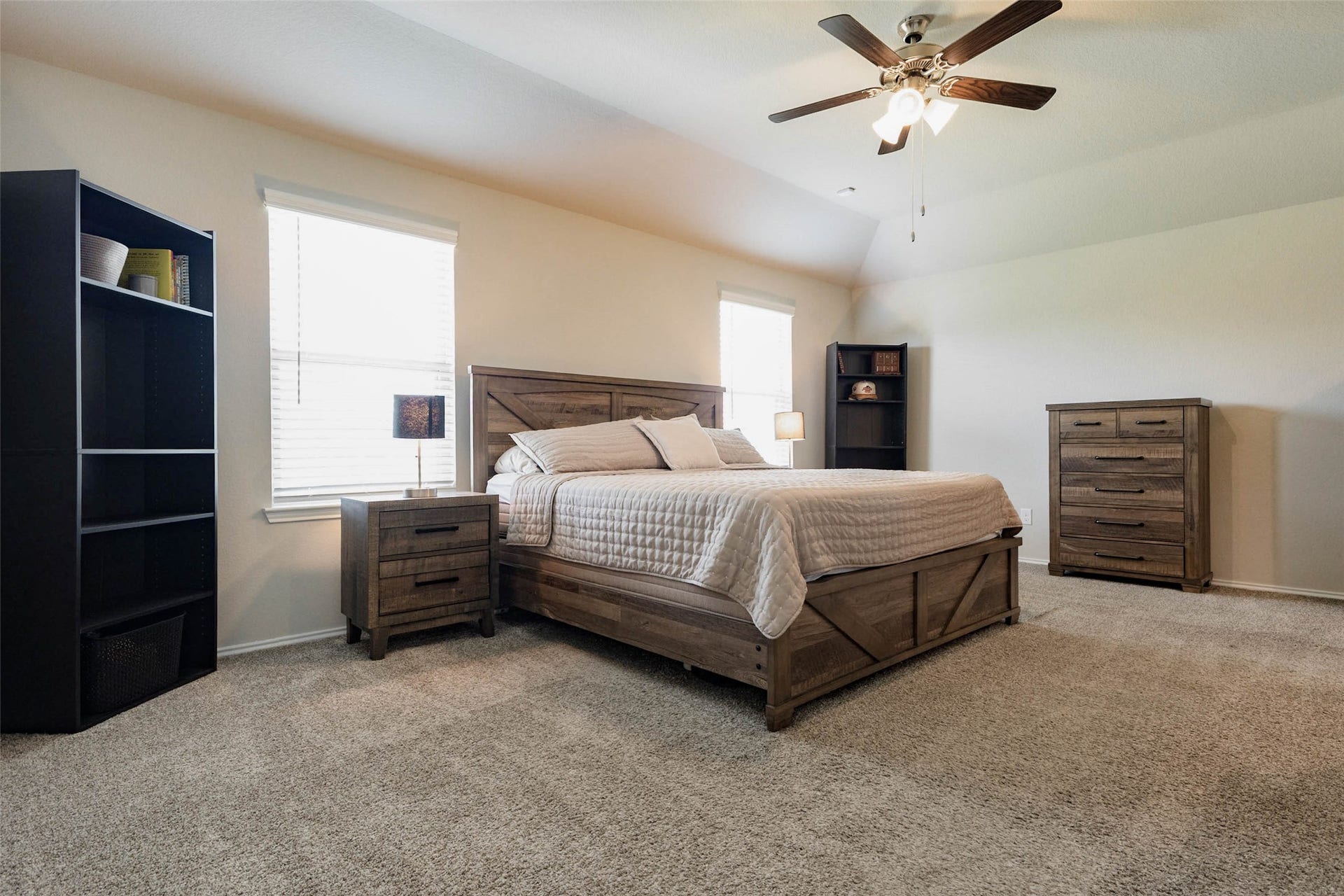 15303 Dinnet Berm Drive, Humble, TX 77346 Welcome to the primary suite, a restful retreat with plush carpet, soft toned walls, and a vaulted ceiling that adds an airy feel. A ceiling fan keeps the room comfortable, and two windows fill the space with sunshine. There is plenty of room for a king size bed along with additional furniture.