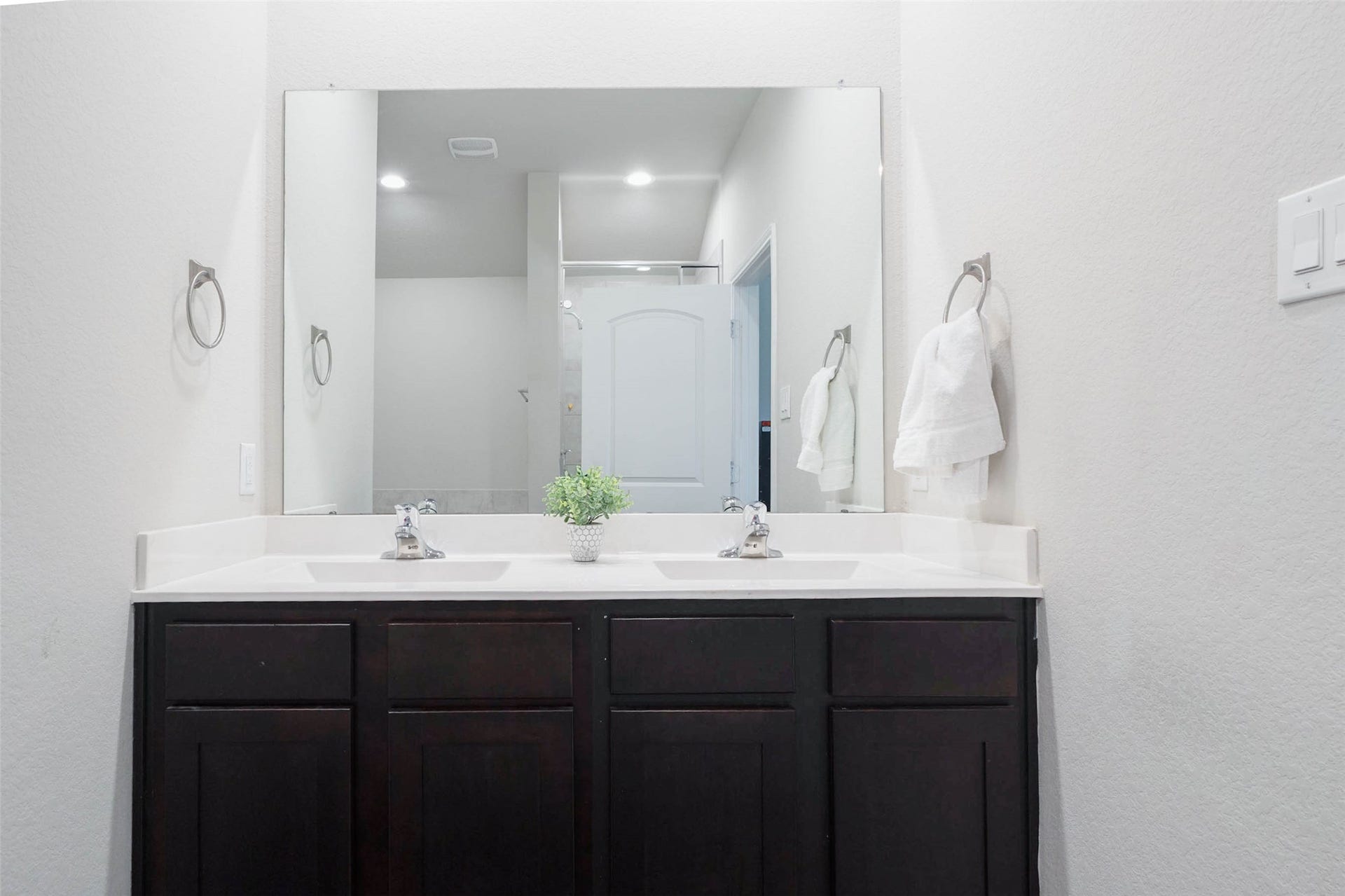 15303 Dinnet Berm Drive, Humble, TX 77346 The primary bathroom also offers a generous vanity with dual sinks, polished chrome fixtures, and crisp white countertops. Dark cabinetry provides ample storage and a striking contrast, while a large mirror adds brightness and makes the space feel open.