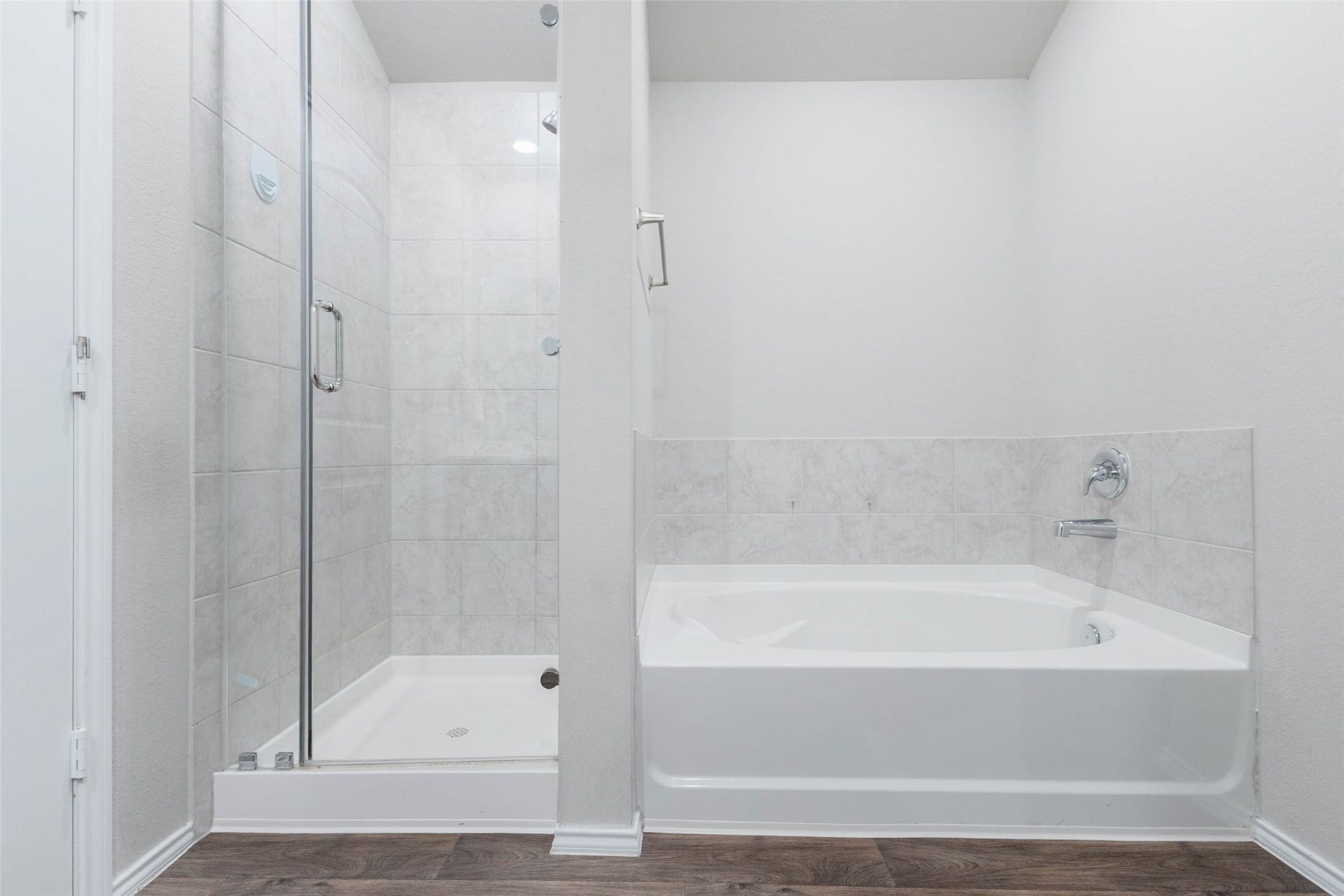 15303 Dinnet Berm Drive, Humble, TX 77346 The spa like primary bathroom is sure to impress, with a deep soaking tub and a separate walk in shower. The shower is enclosed in glass and surrounded by light tile that extends all the way up to the ceiling, creating a clean and luxurious look.