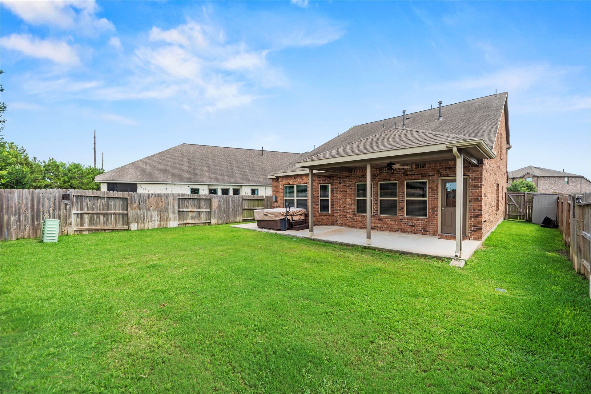 6418 Shadowbrook Hollow Trail, Katy, TX 77493 This rear view underscores the scope of the fully fenced yard, highlighted by a professional underground sprinkler system and a dedicated, built-in outdoor spa/hot tub.