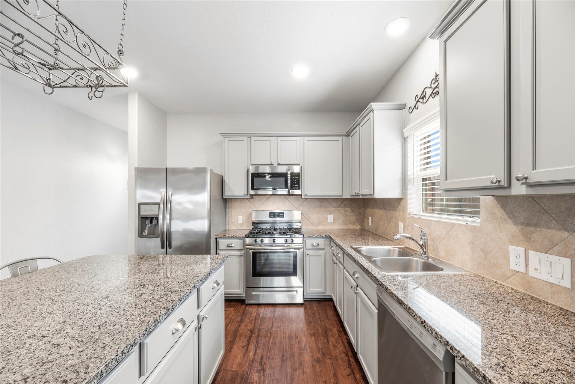 6418 Shadowbrook Hollow Trail, Katy, TX 77493 Another angle of the beautifully appointed kitchen reveals timeless tile backsplashes, a deep double-bowl stainless sink positioned under a bright window, under-cabinet lighting, and a layout carefully designed to maximize prep space.